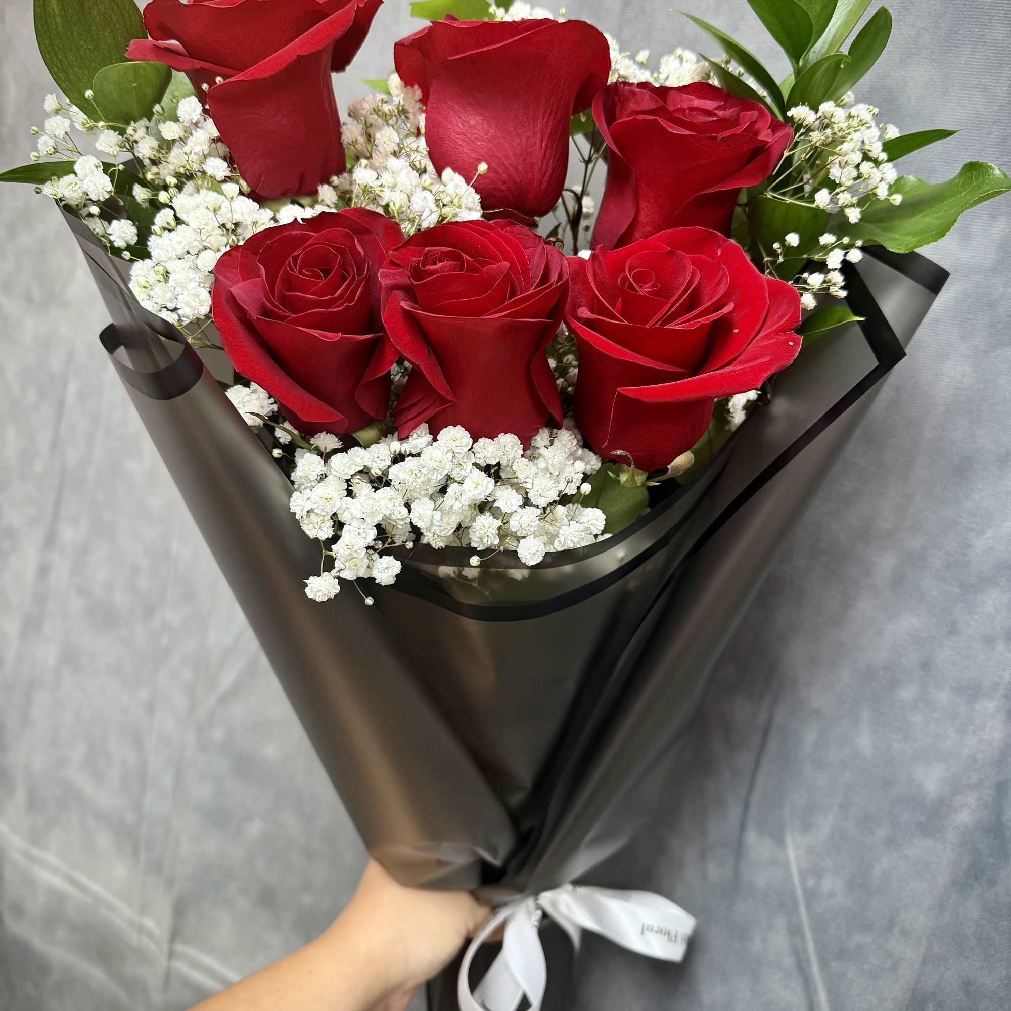 Bouquet of red roses with white baby's breath in black wrap