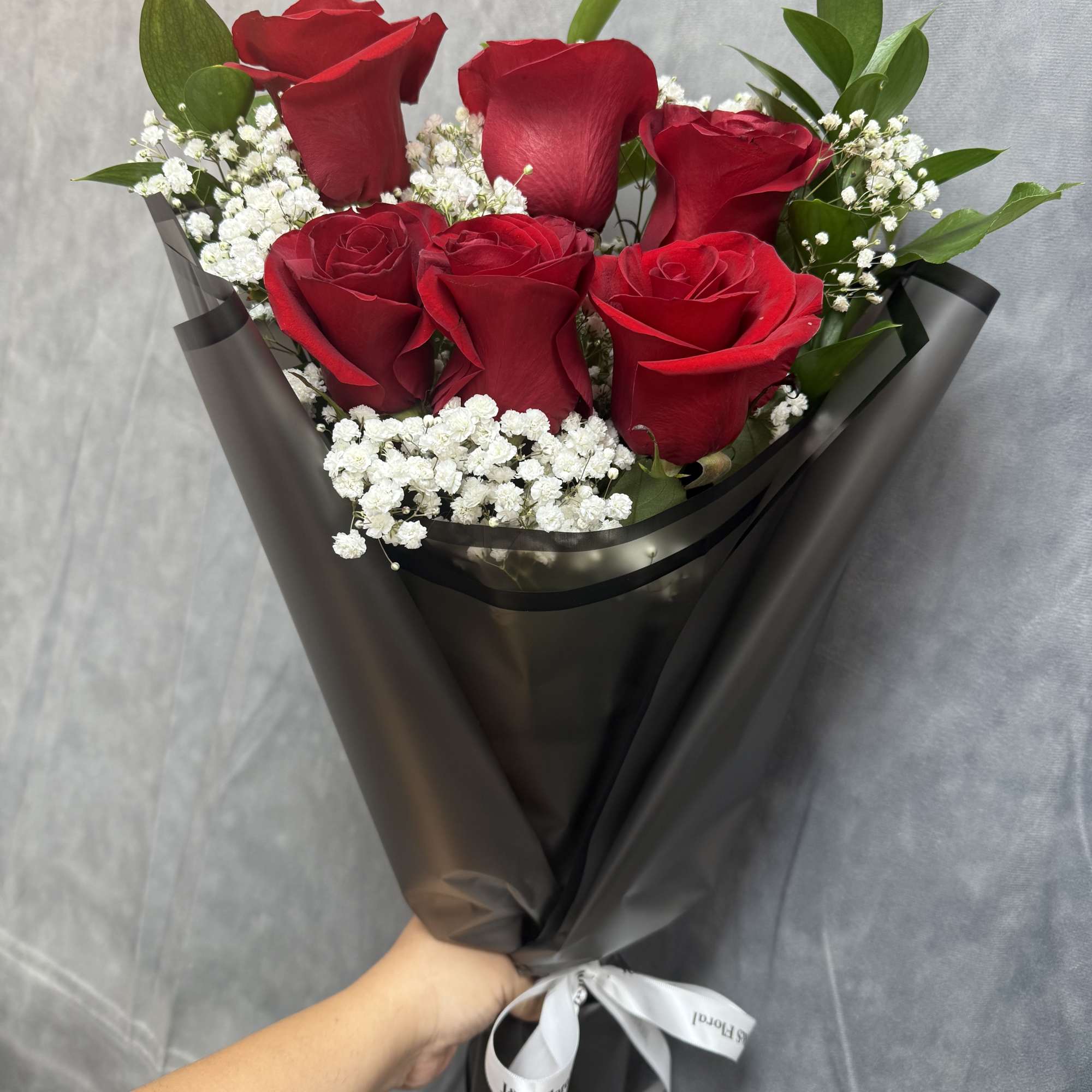 Bouquet of red roses with white baby's breath in black wrap
