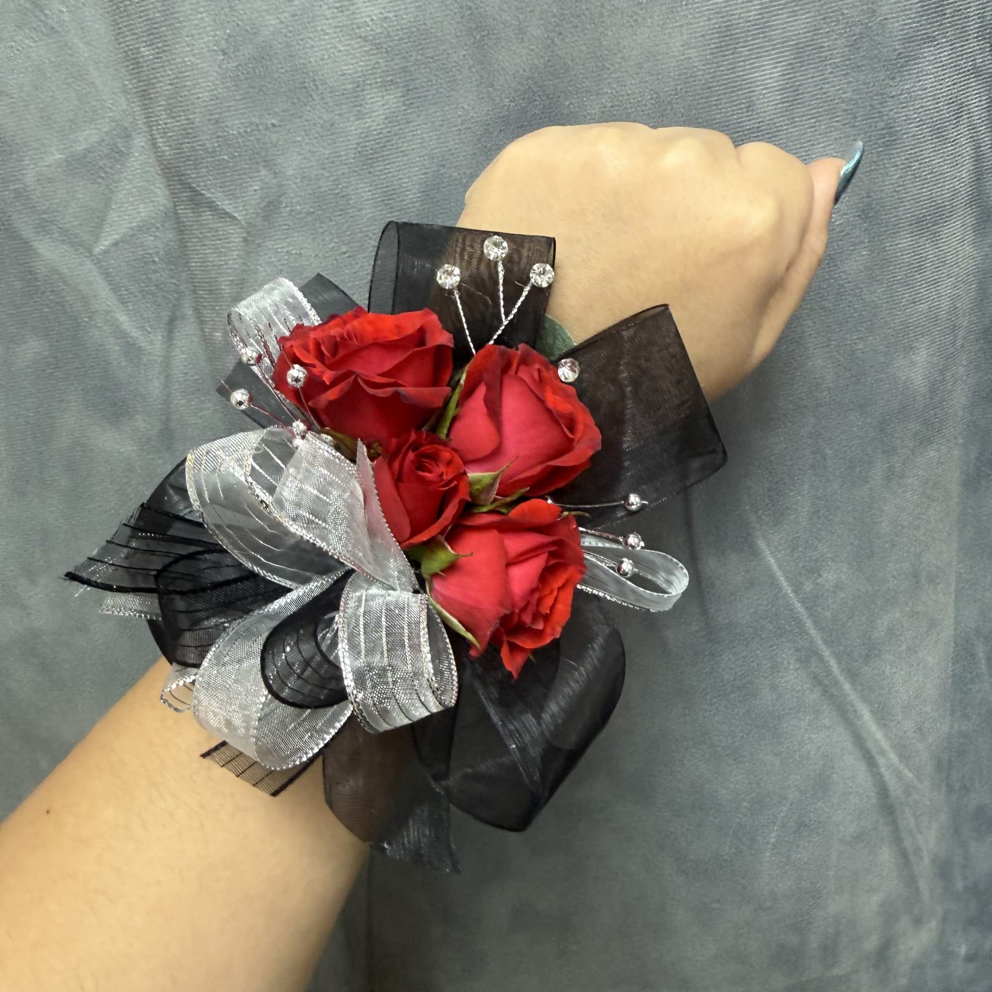 Red spray roses with black and silver ribbon and bead accents on
