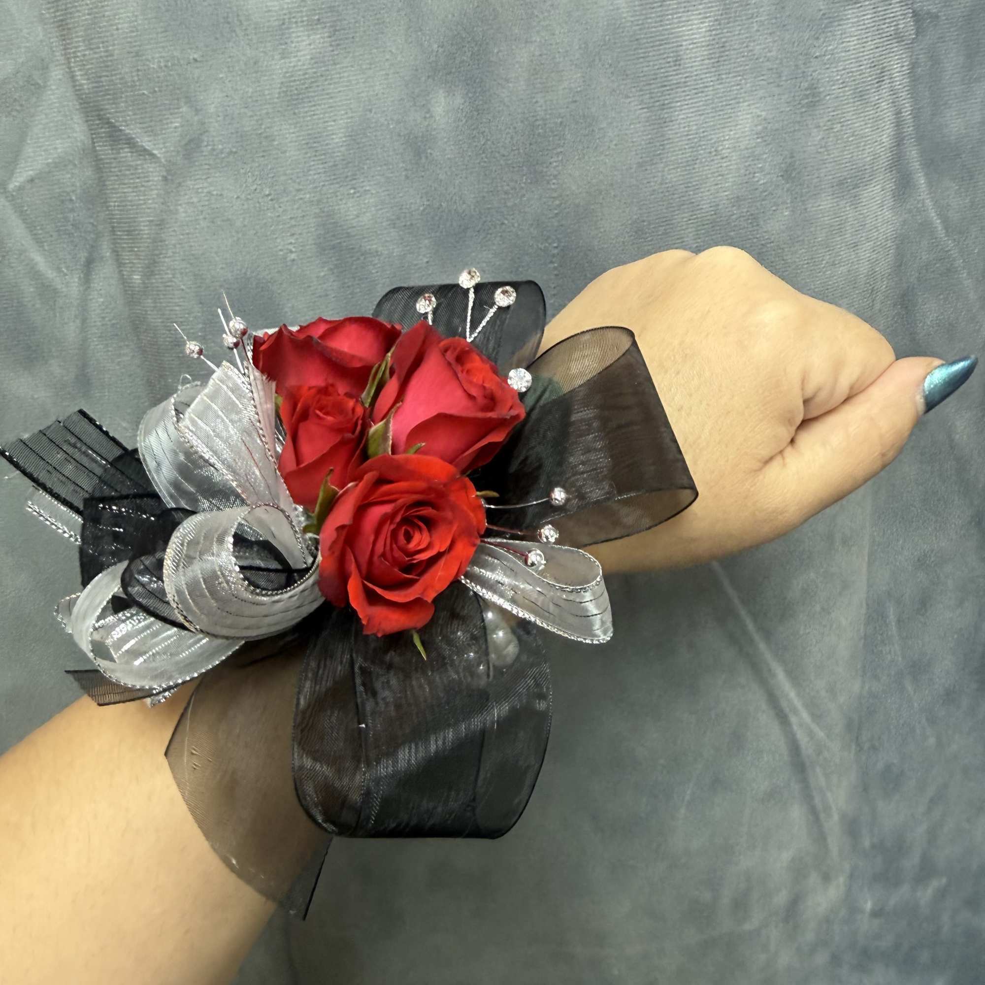 Red spray roses with black and silver ribbon and bead accents on