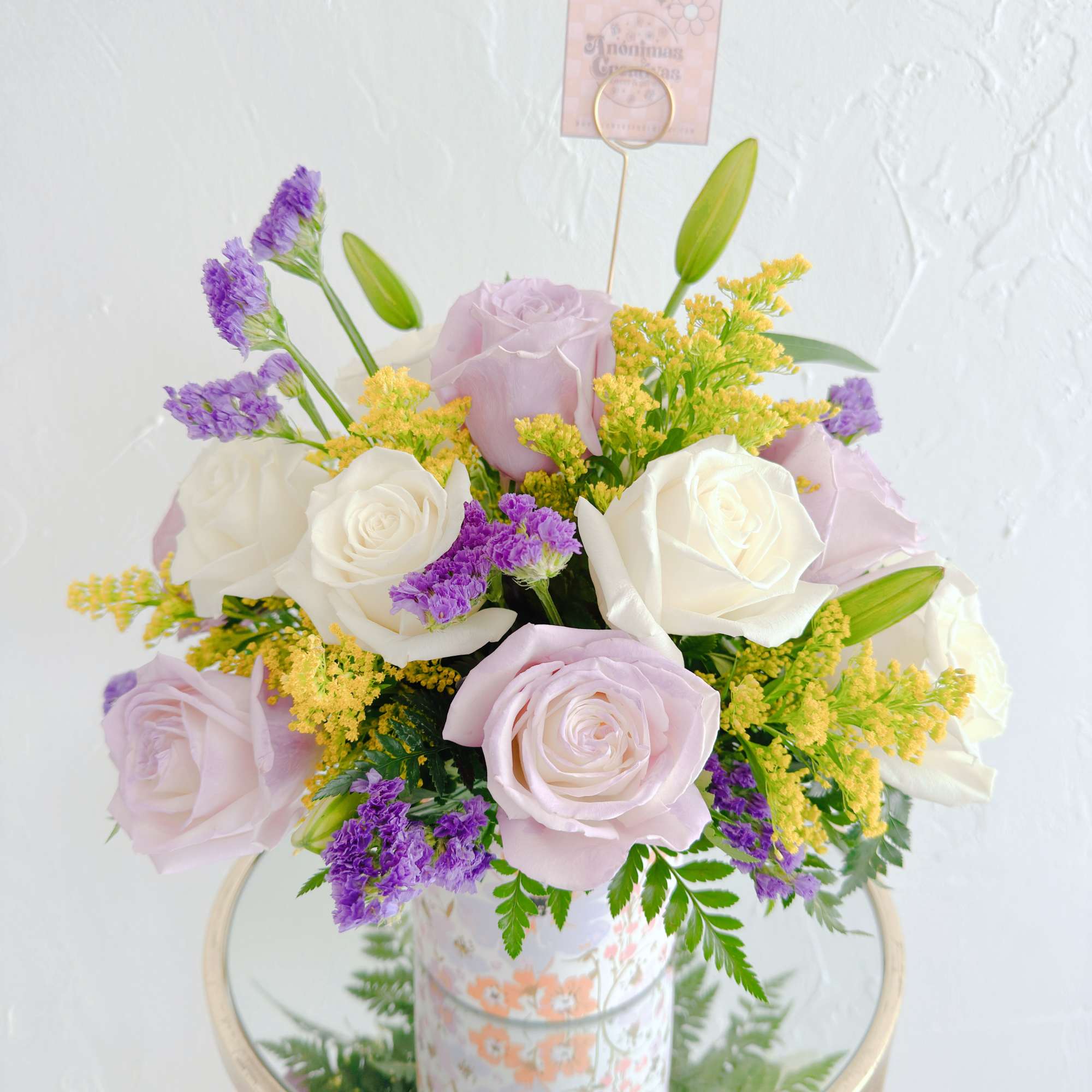 Charming floral arrangement featuring soft lavender and white roses, accented with vibrant