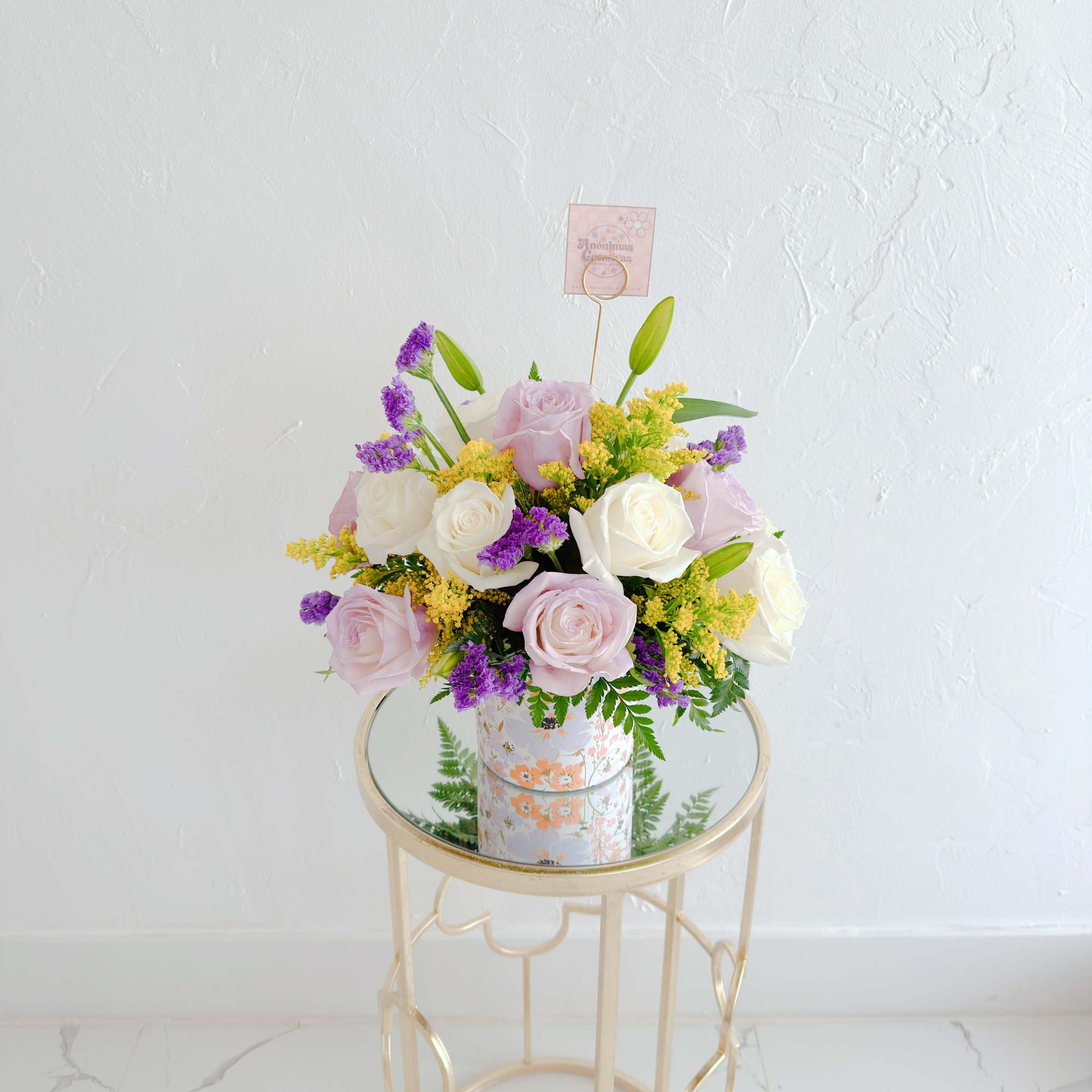Charming floral arrangement featuring soft lavender and white roses, accented with vibrant