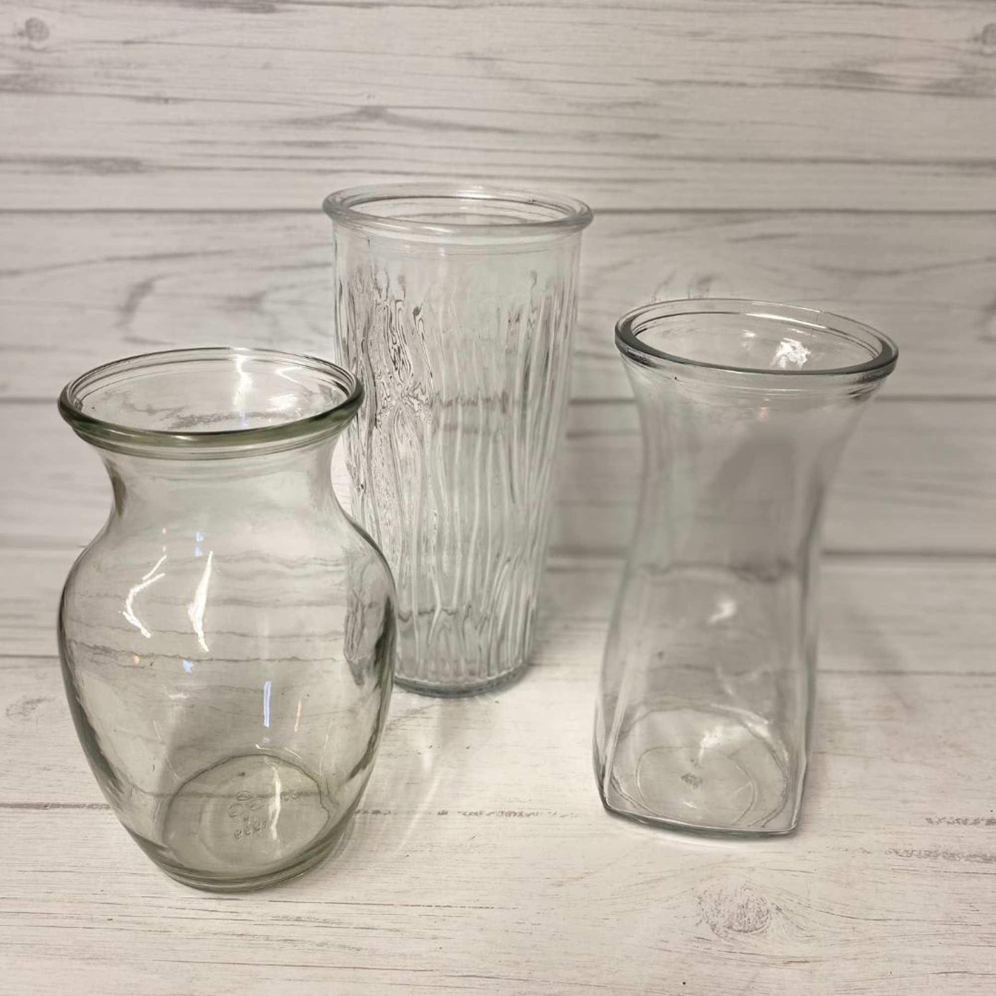 Three clear glass vases on a white wood surface