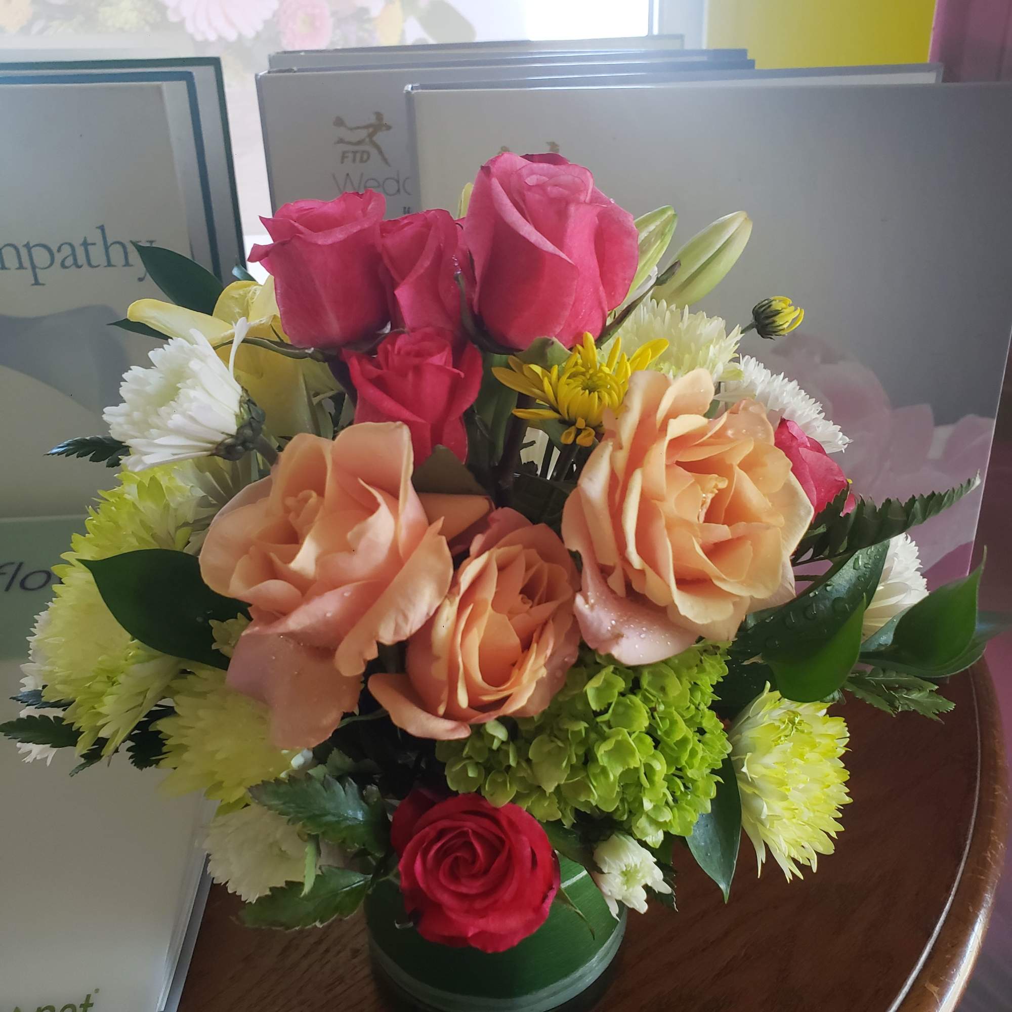 Hot pink and peach roses take center stage in this rounded sympathy