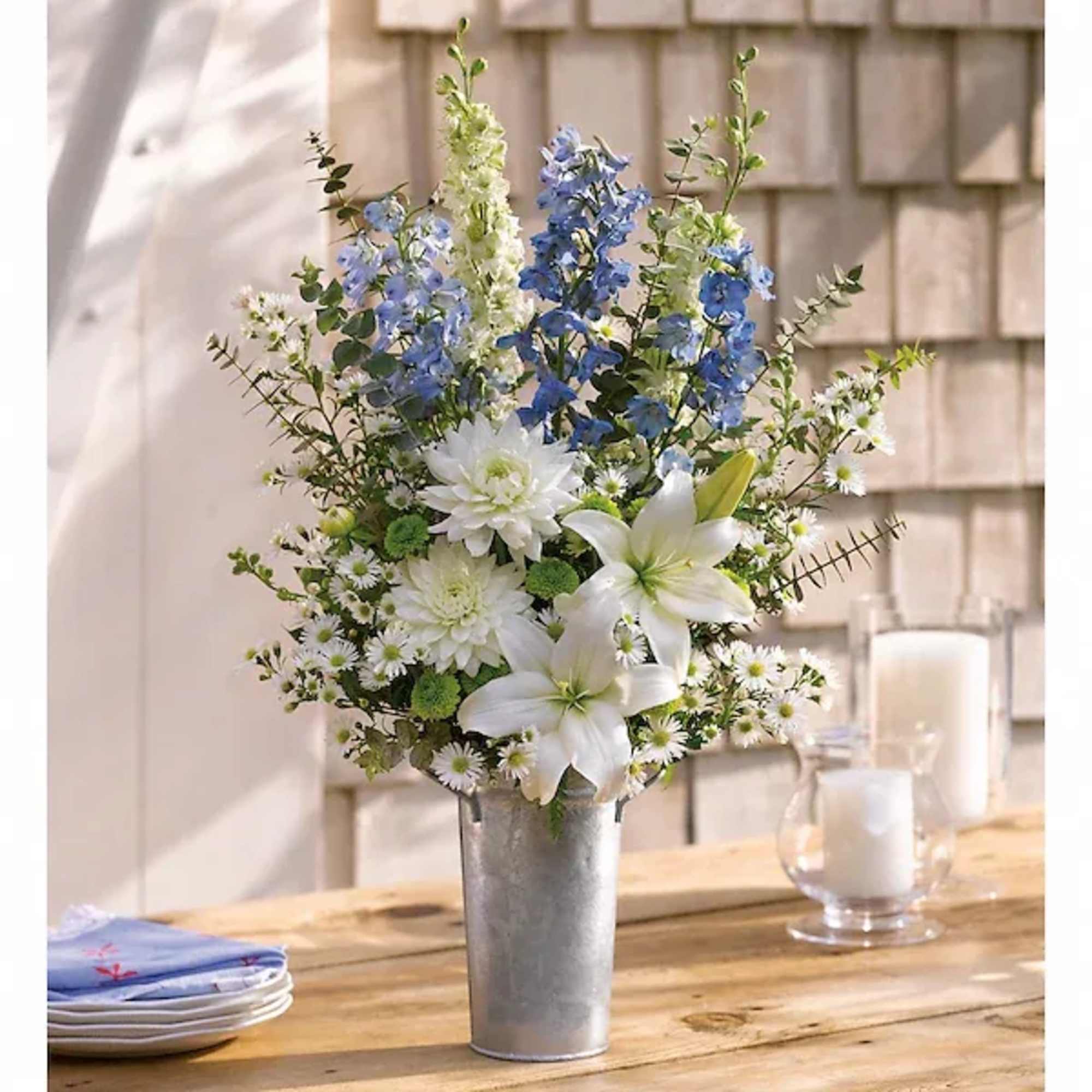 White lilies and blue flowers arranged in a metal vase