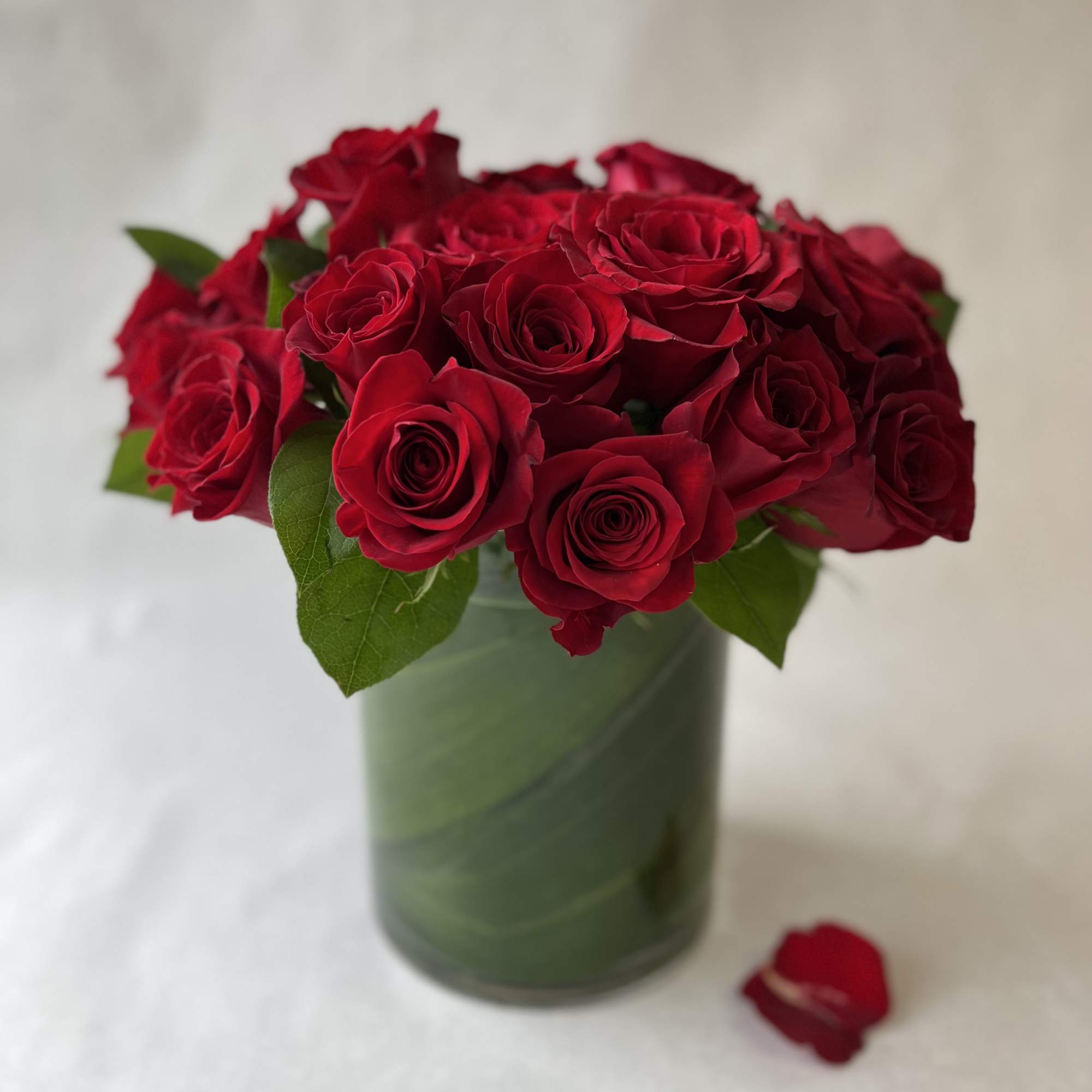 Red roses arranged in a green glass vase