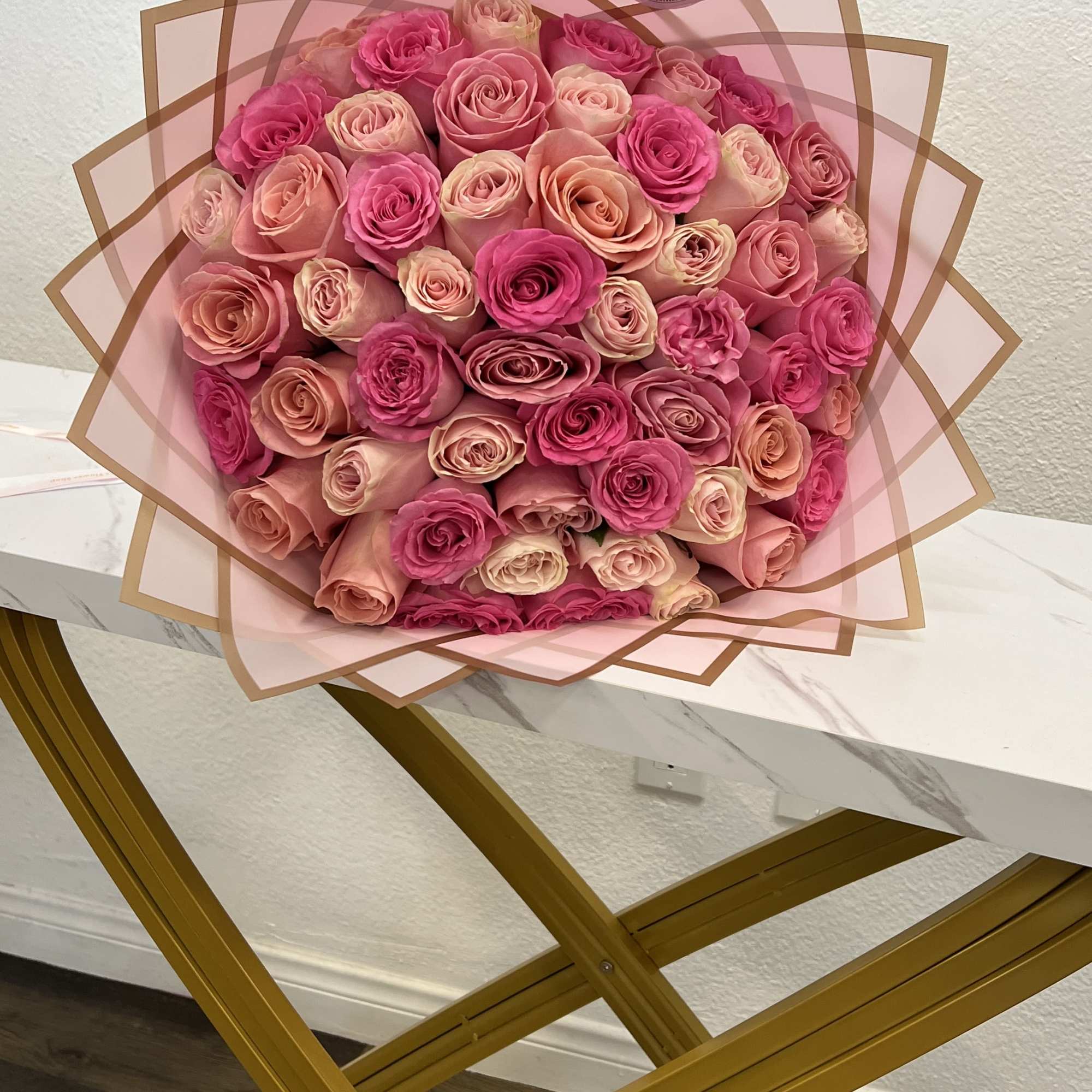 Large bouquet of pink and peach roses wrapped in translucent pink paper