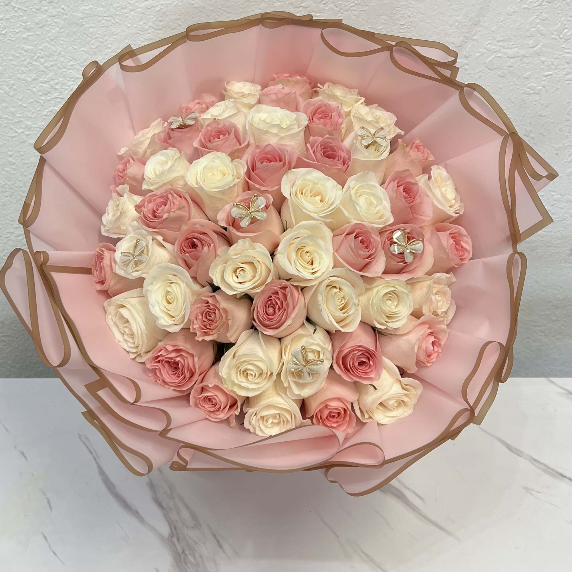 Bouquet of pink and cream roses wrapped in pink paper