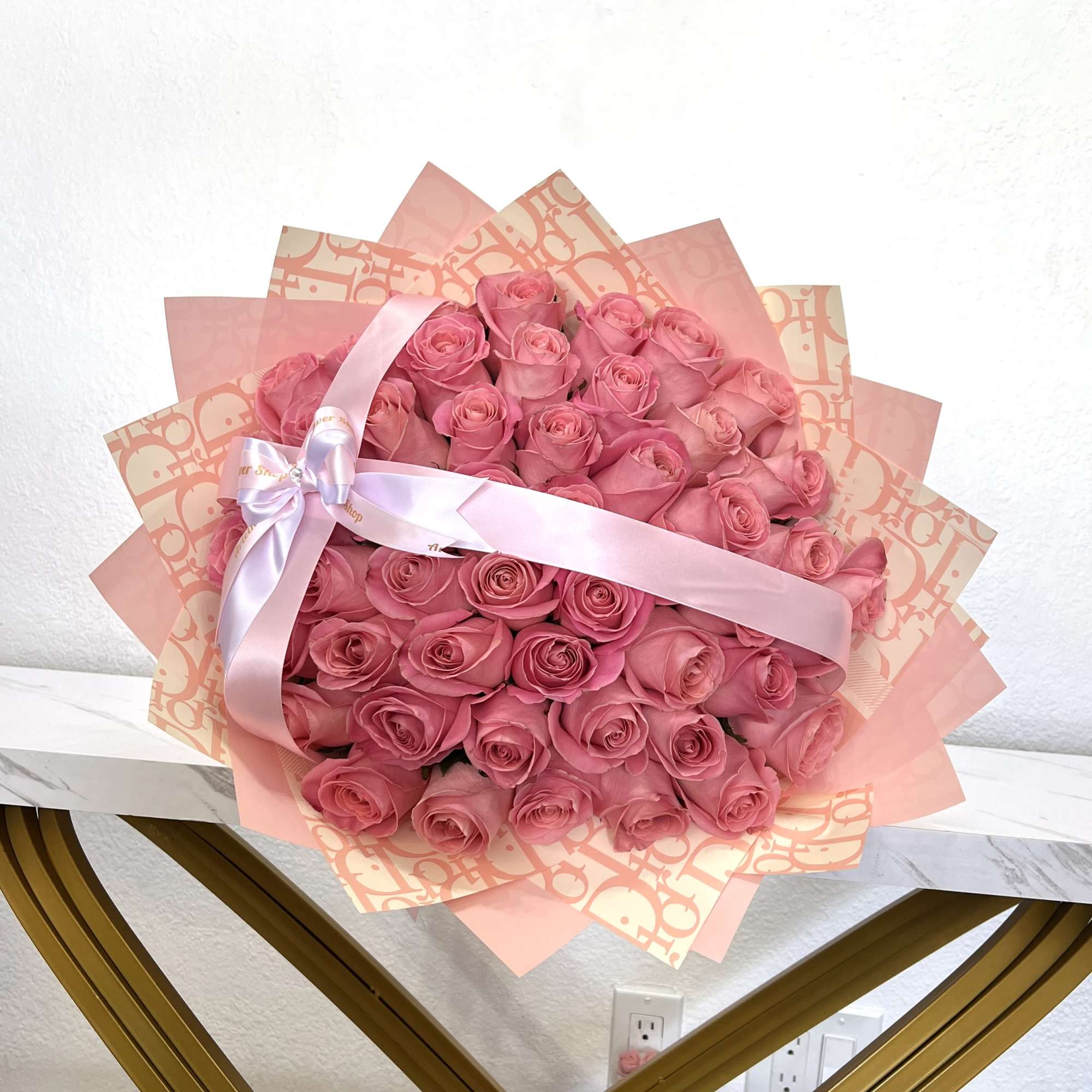 Large bouquet of pink roses wrapped in pink paper with a satin ribbon