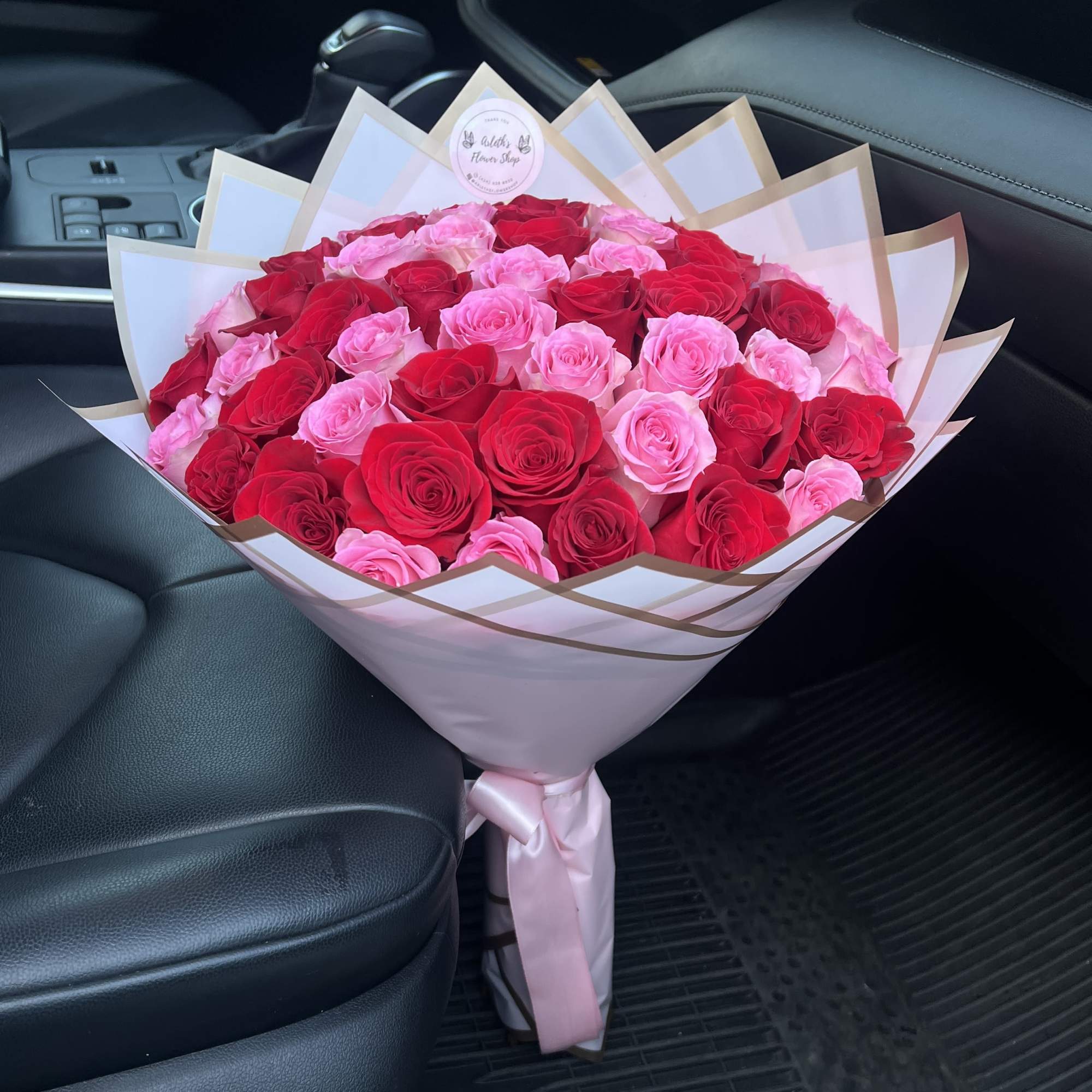 Large bouquet of pink and red roses wrapped in white paper