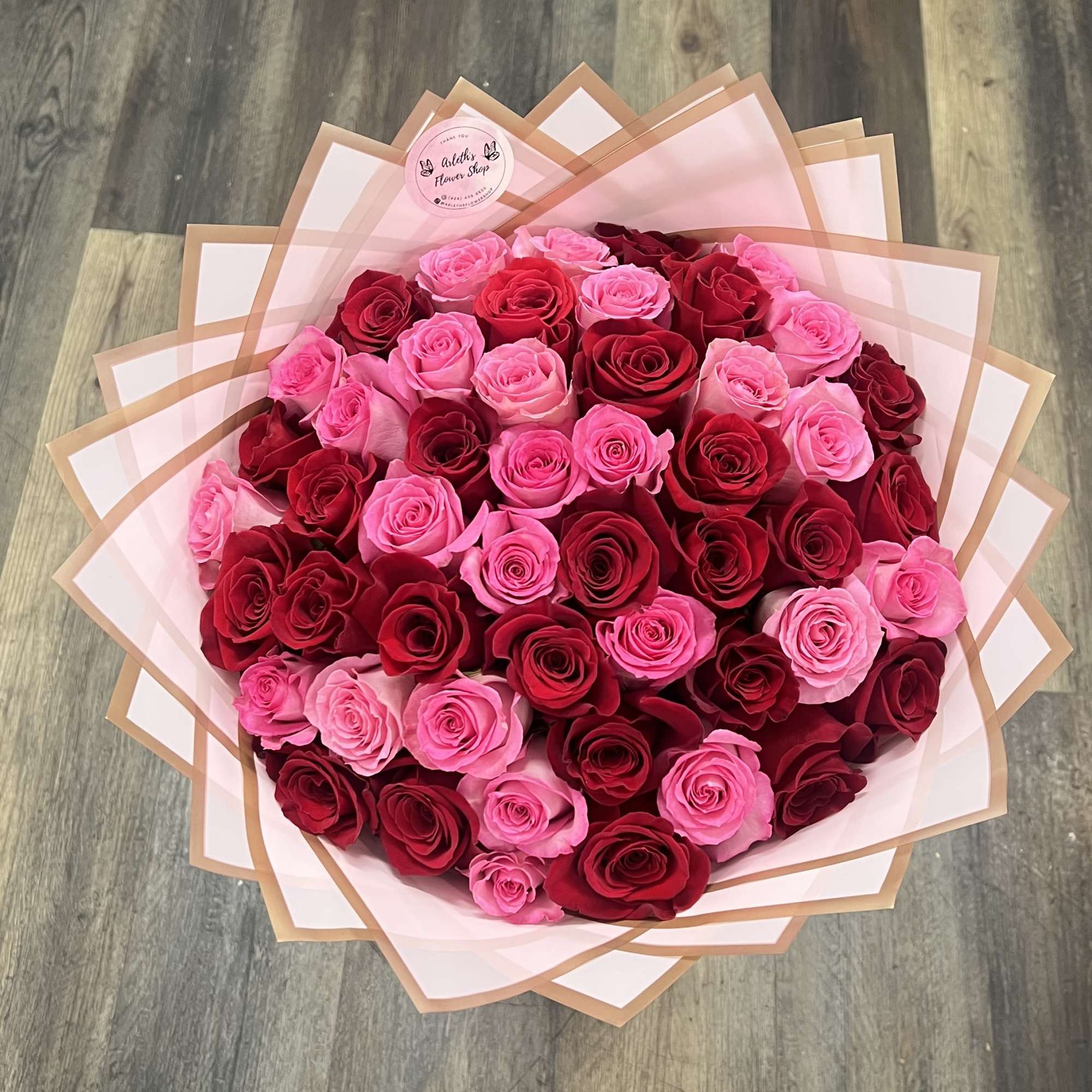 Large bouquet of pink and red roses wrapped in pale pink paper