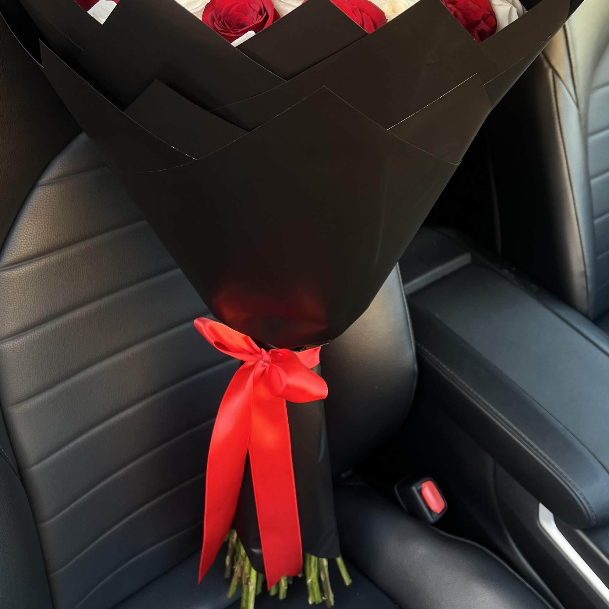 Bouquet of red and white roses wrapped in black paper with a red ribbon