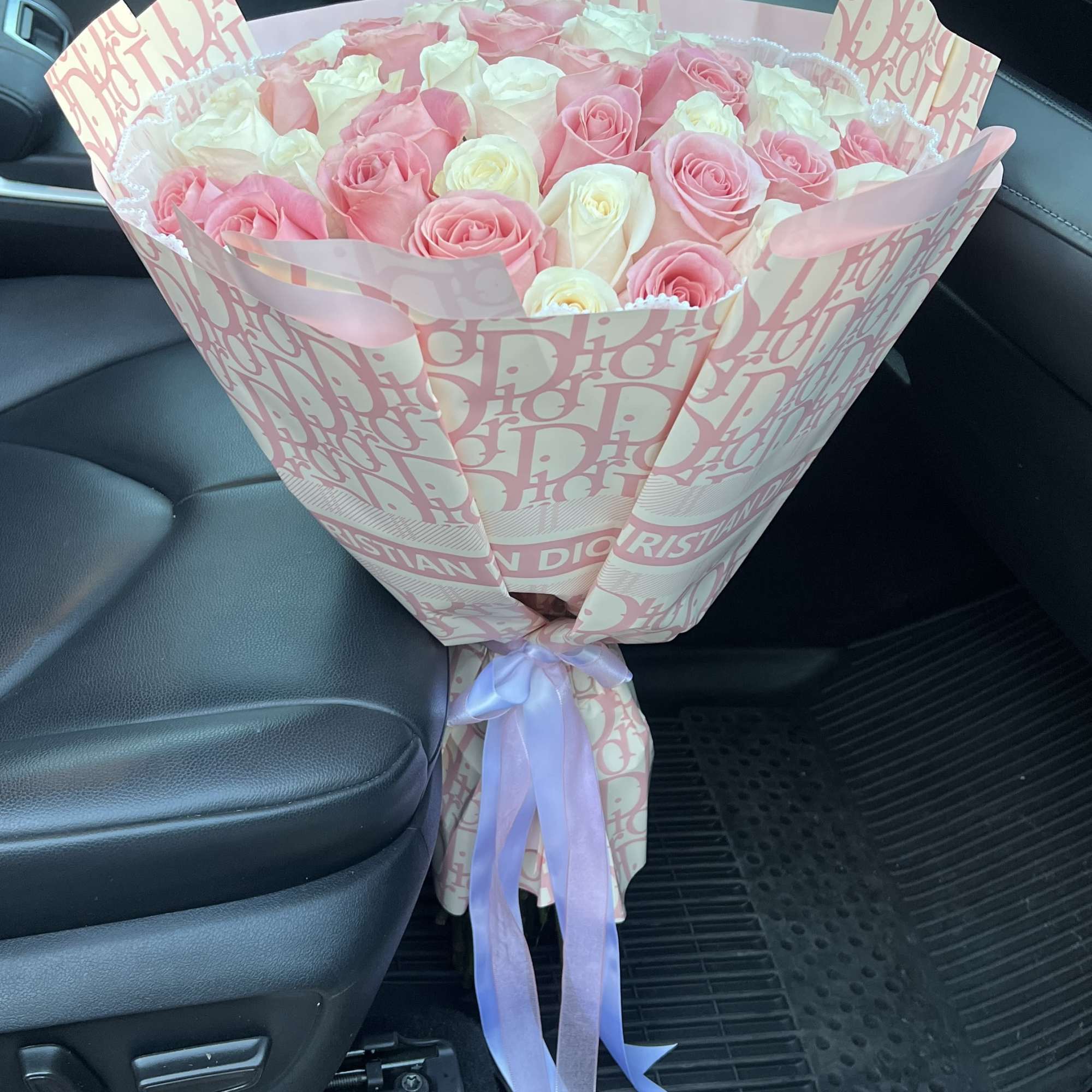 Pink and white rose bouquet wrapped in patterned paper with a ribbon