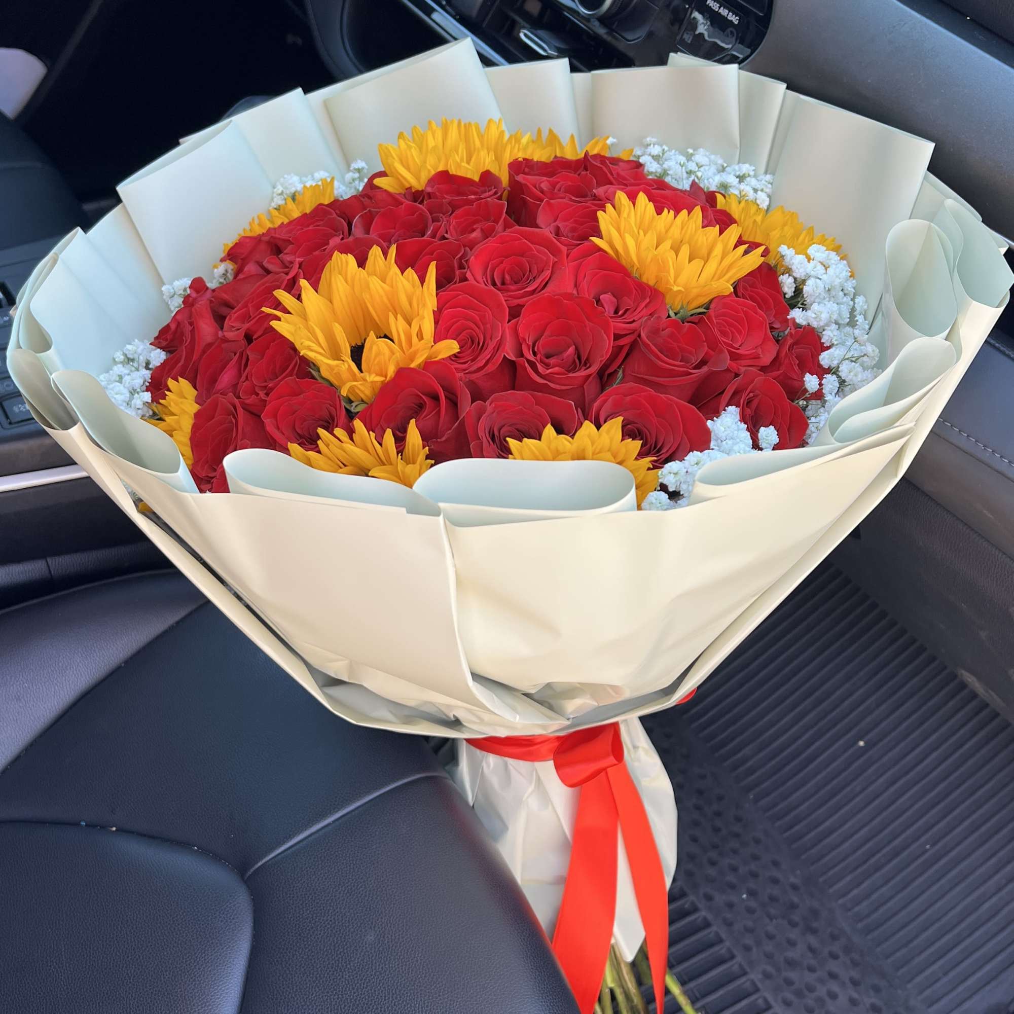 Bouquet of red roses and yellow flowers wrapped in cream paper