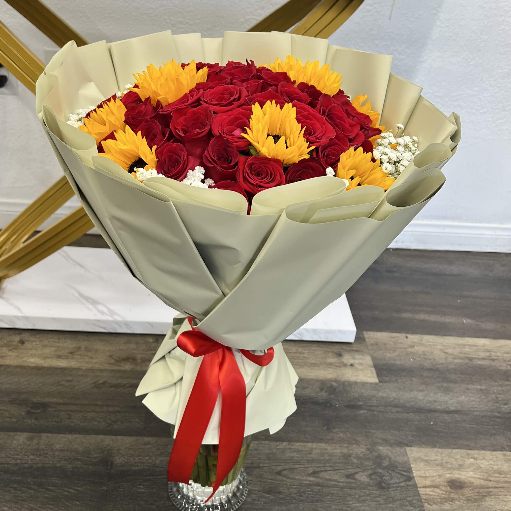 Bouquet of red roses and yellow sunflowers wrapped in cream paper