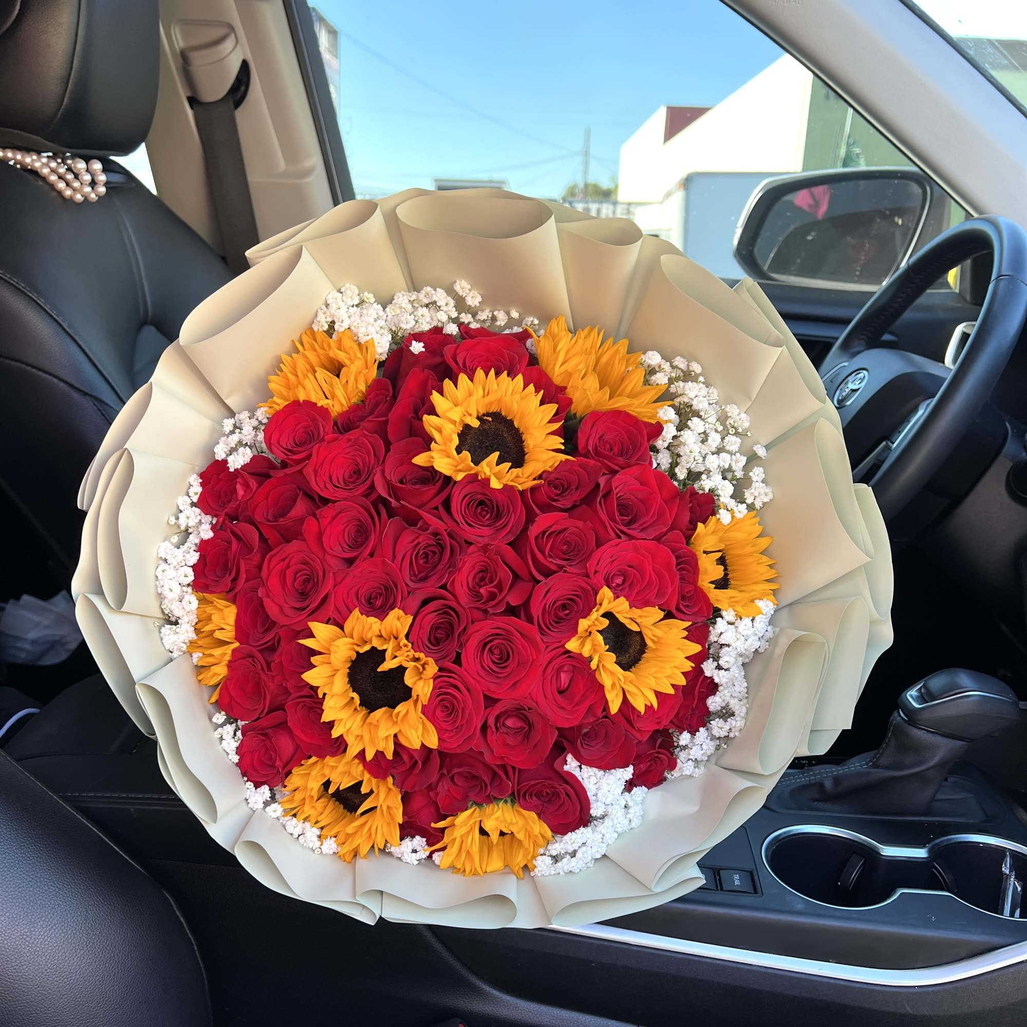 Bouquet of red roses and yellow sunflowers wrapped in beige paper