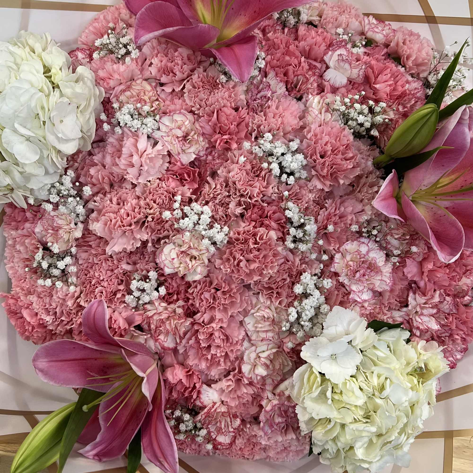 Pink carnation bouquet with lilies and white hydrangeas in decorative wrap