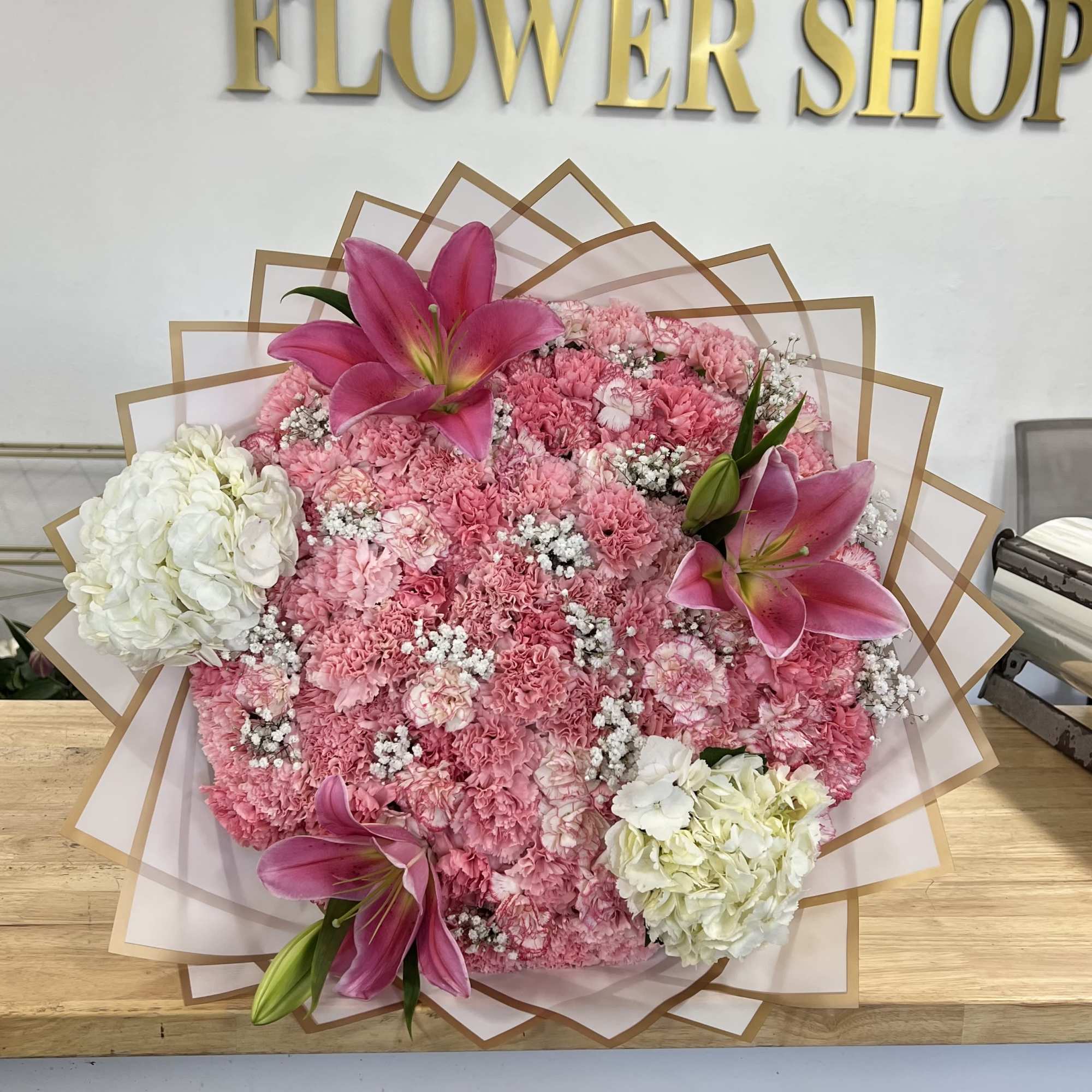 Pink carnation bouquet with lilies and white hydrangeas in decorative wrap