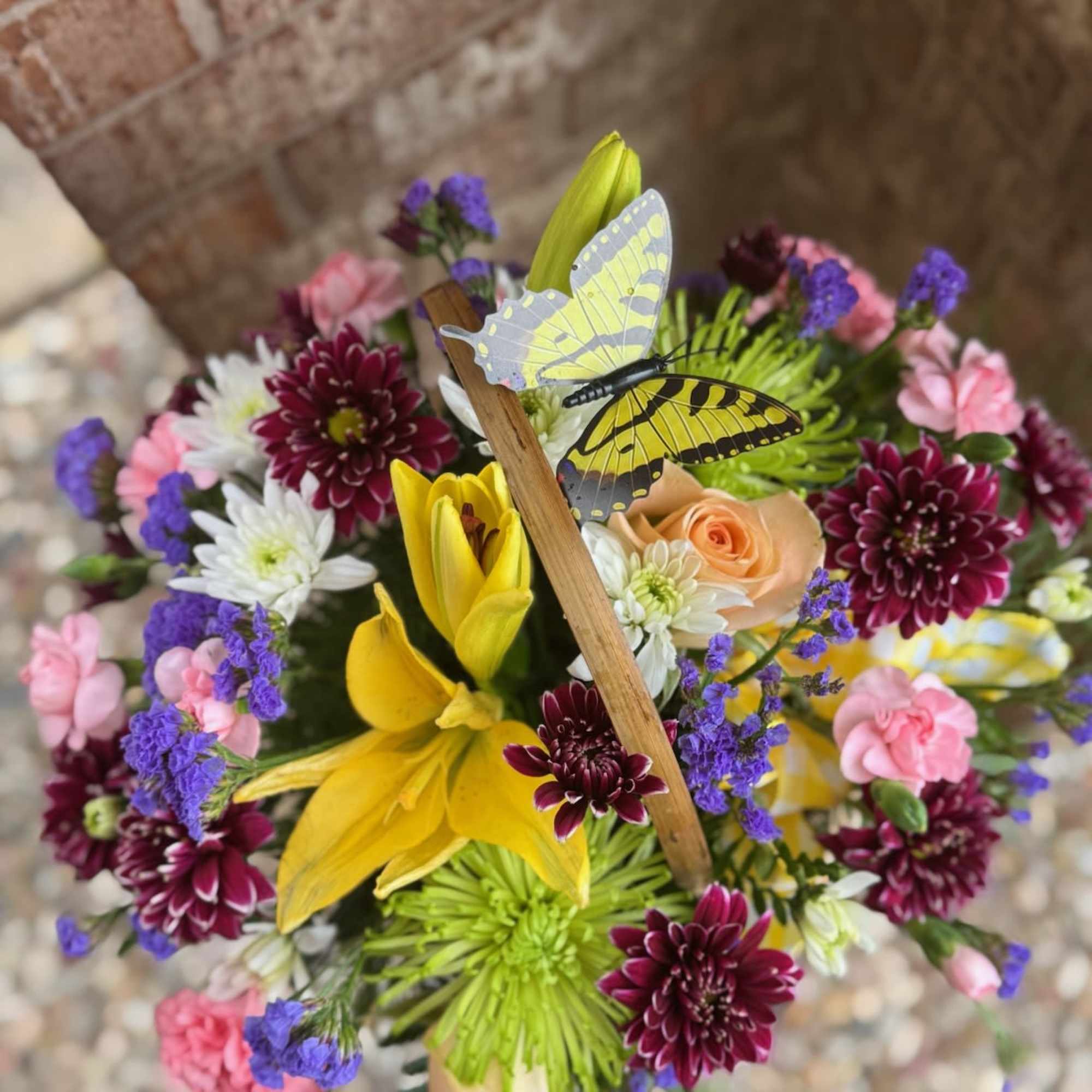 Mixed bouquet with yellow lilies, roses, and a butterfly pick