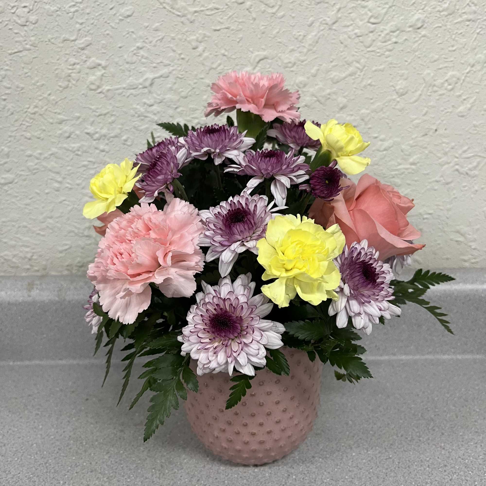 This cheerful dome of pastel blooms includes pink carnations, lavender-and-white chrysanthemums, sunny