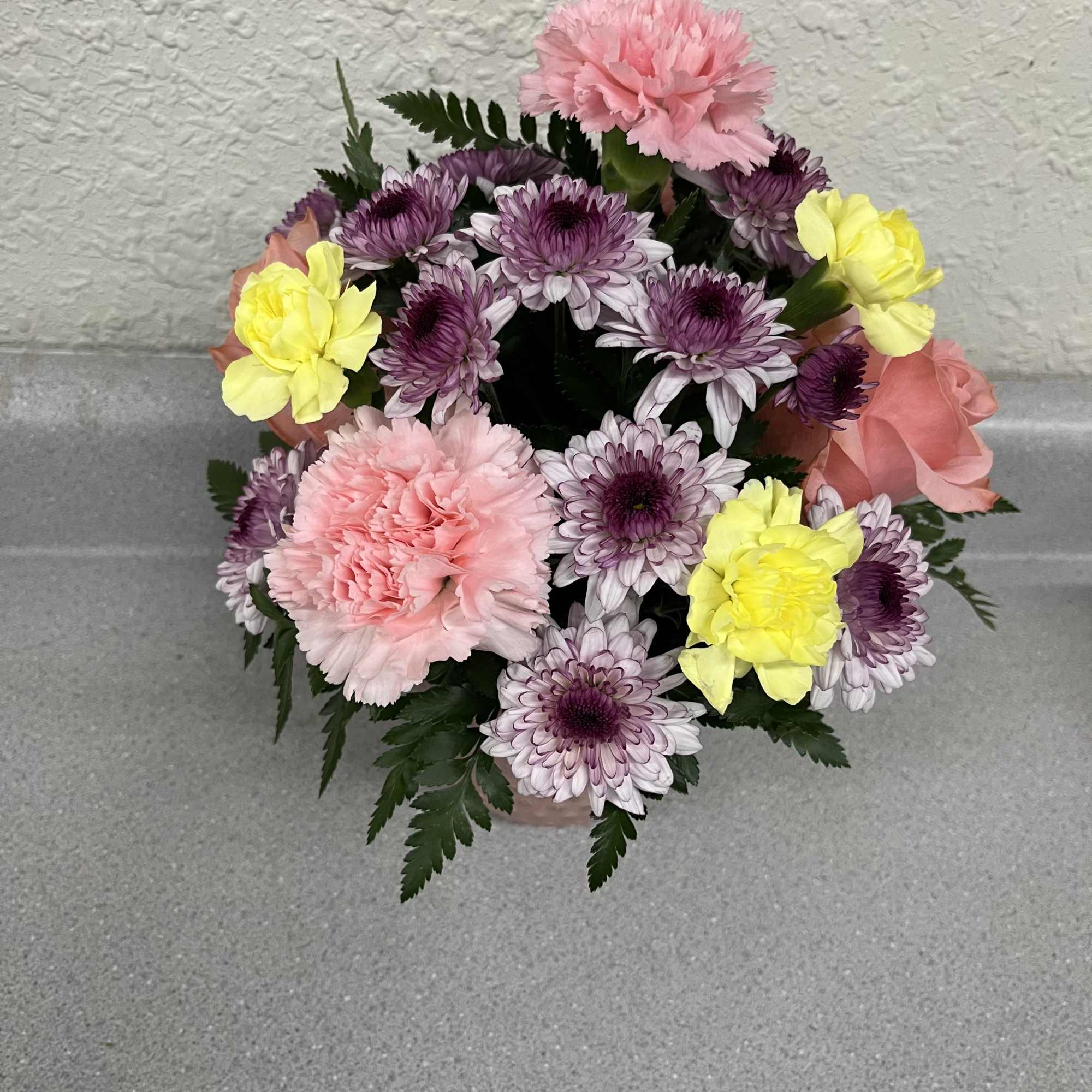 This cheerful dome of pastel blooms includes pink carnations, lavender-and-white chrysanthemums, sunny