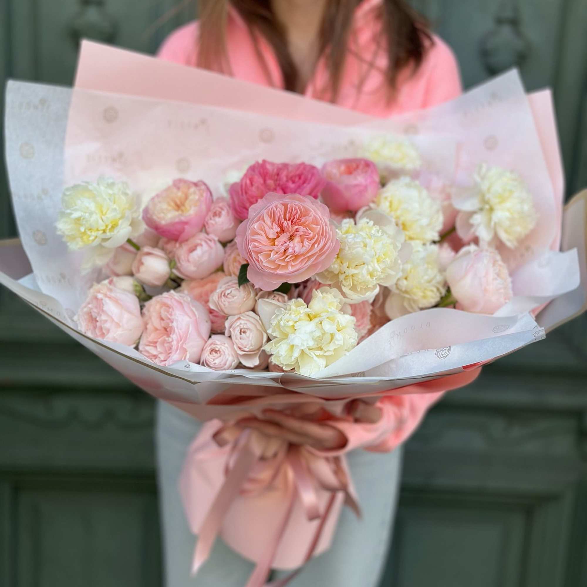 Large pastel bouquet of pink and cream roses and peonies in a pink hatbox with ribbons.