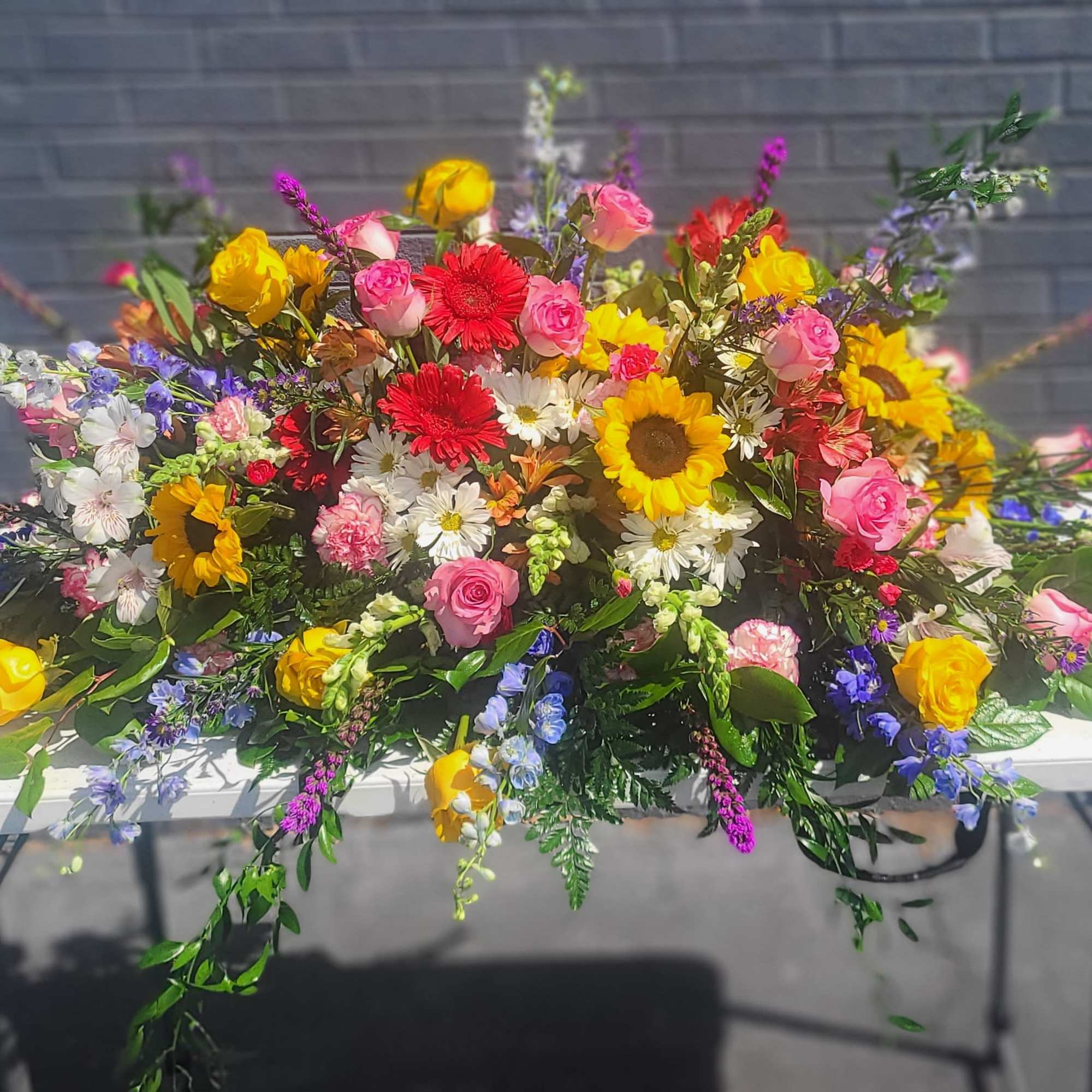  Casket Spray with sunflowers, roses, daisies and mixed spring bloom