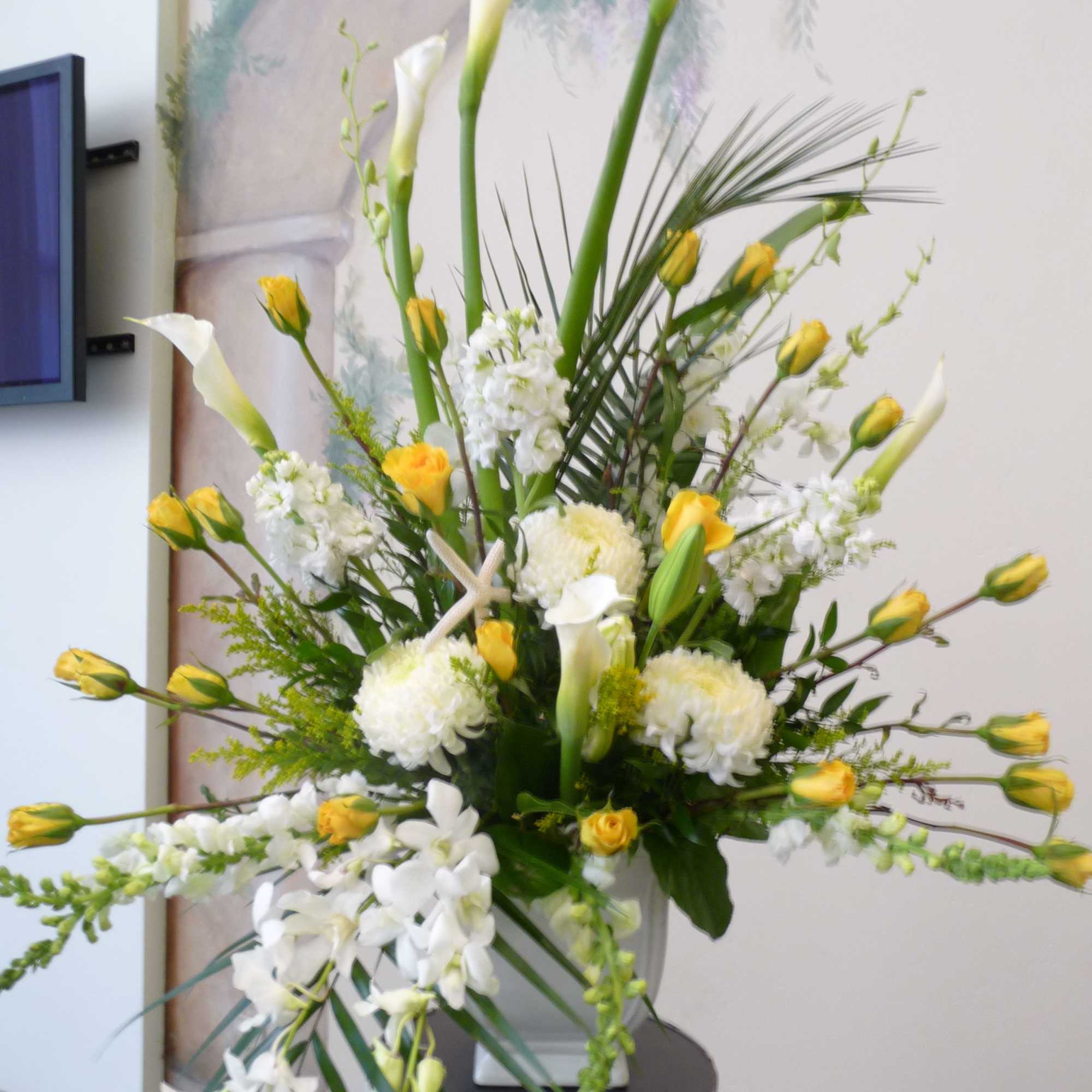 Tall white and yellow floral arrangement in a white vase