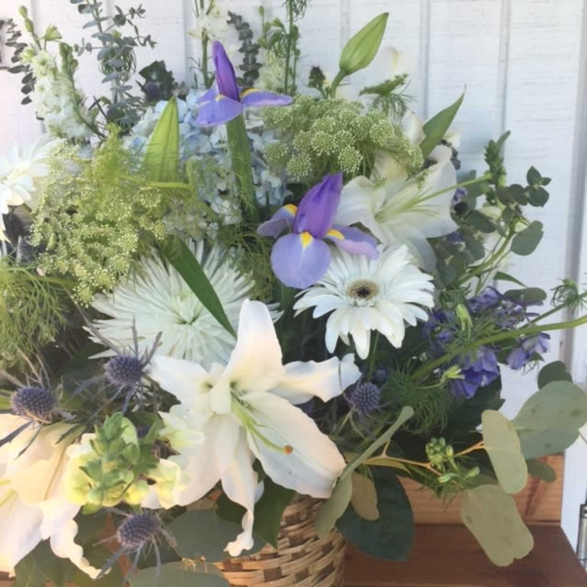 Basket arrangement with white lilies, white daisies, and purple irises