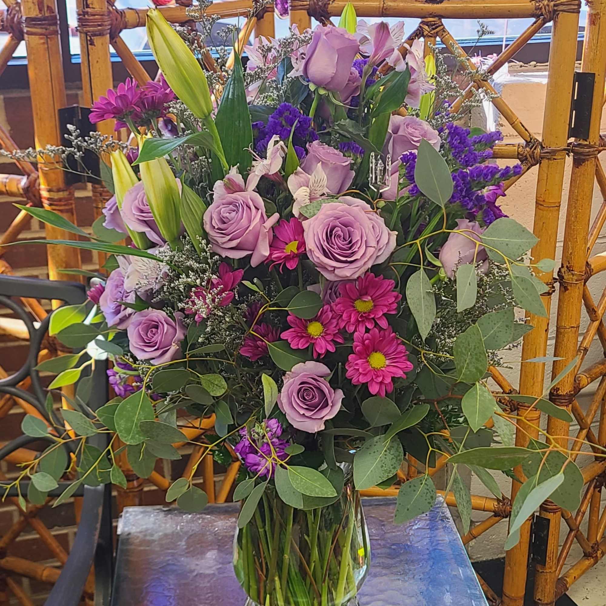 Lavender roses blended with pale lily buds and bright magenta daisy mums