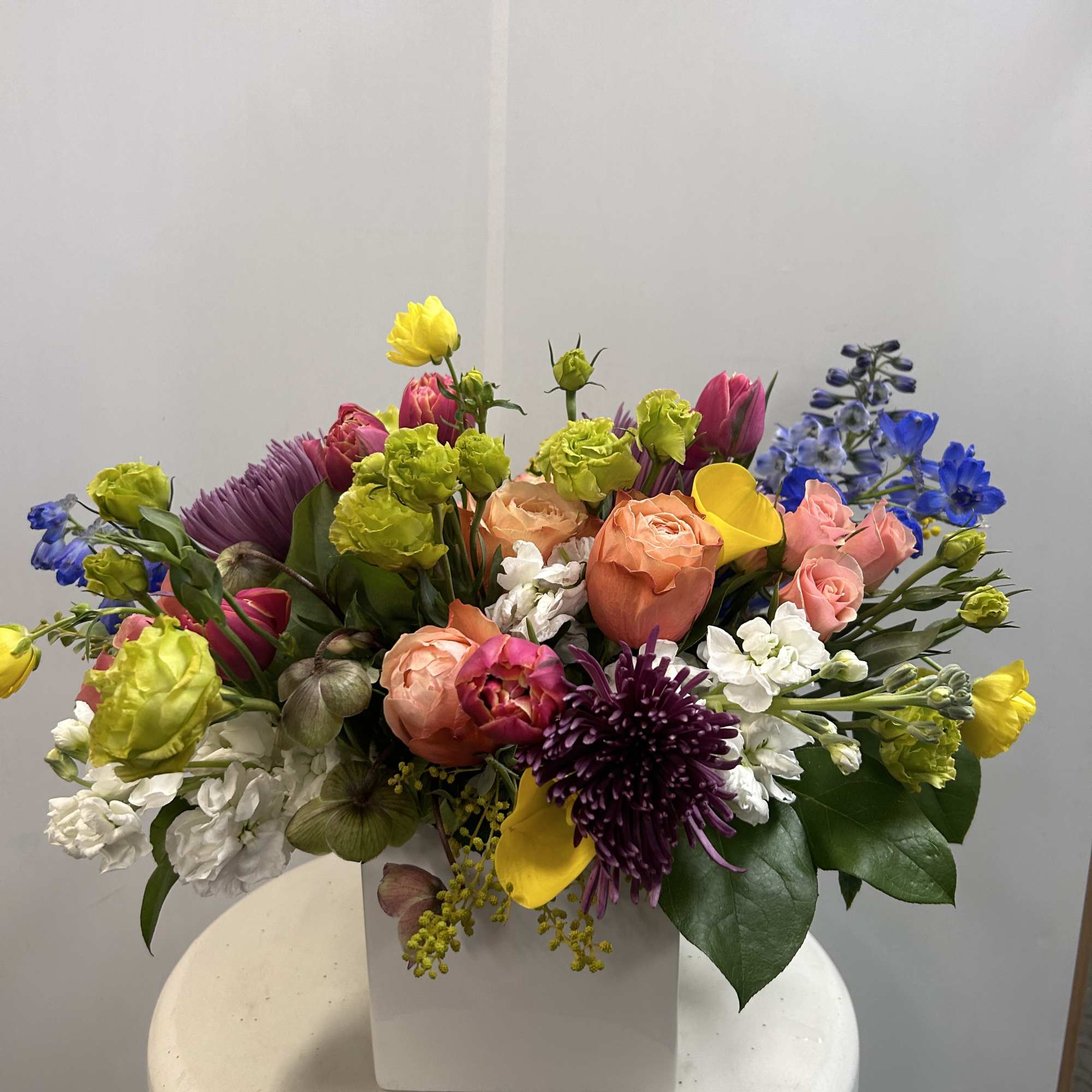 Colorful mixed flower arrangement in a white square vase