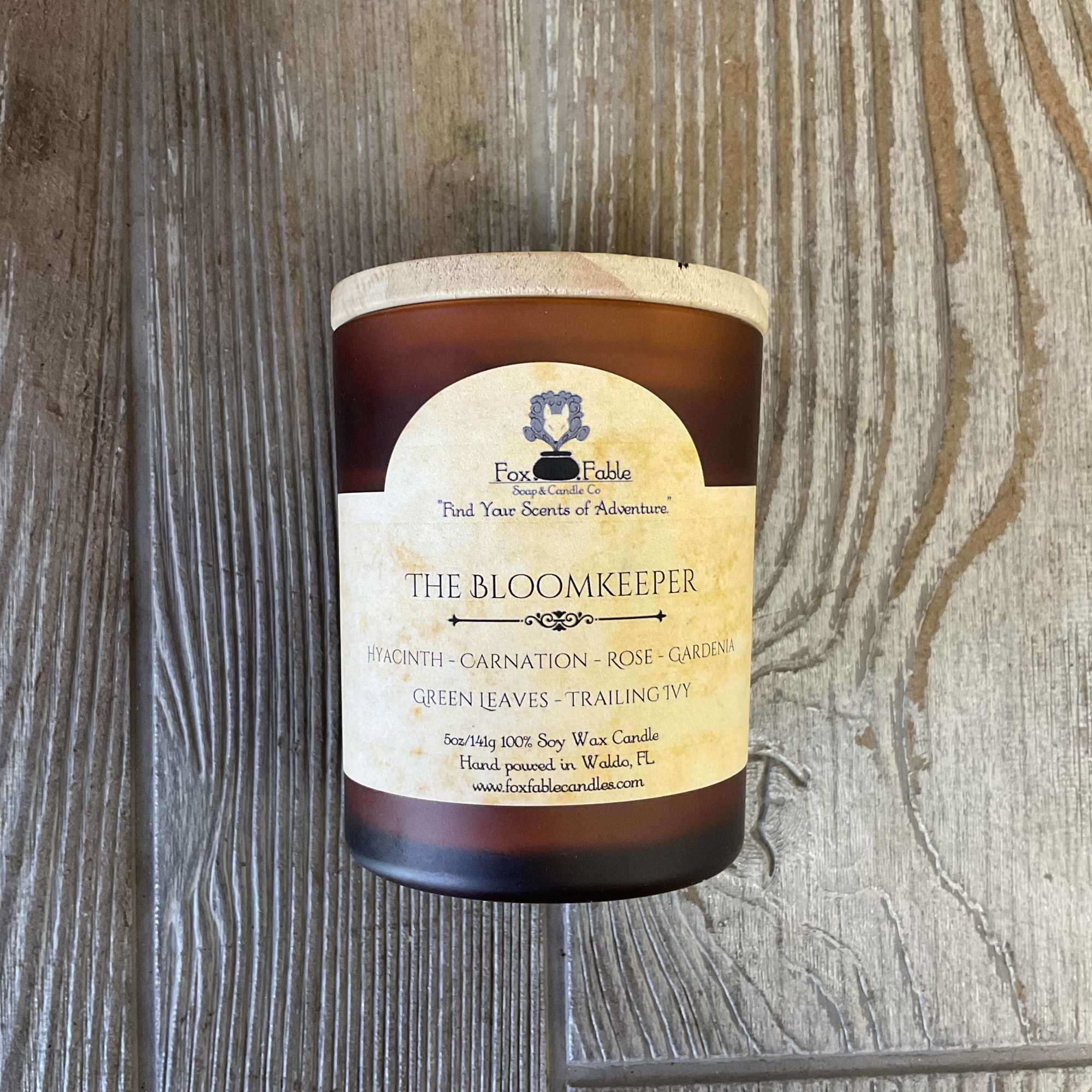 Brown glass candle jar with a cream label on a wood surface