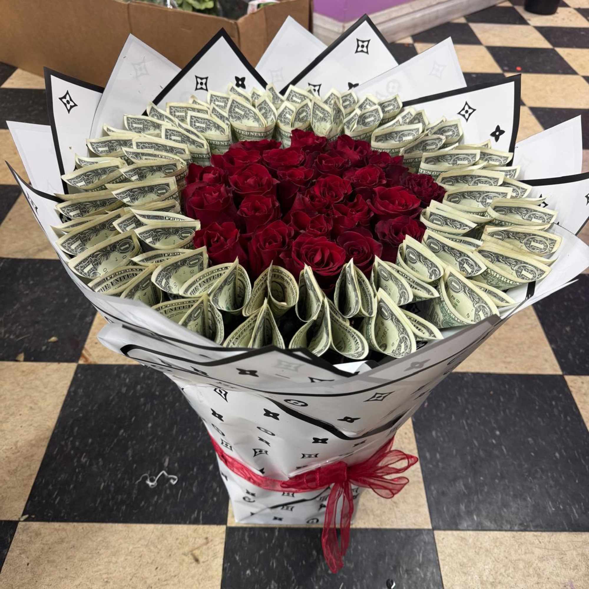 Bouquet of red roses wrapped with folded dollar bills and white paper