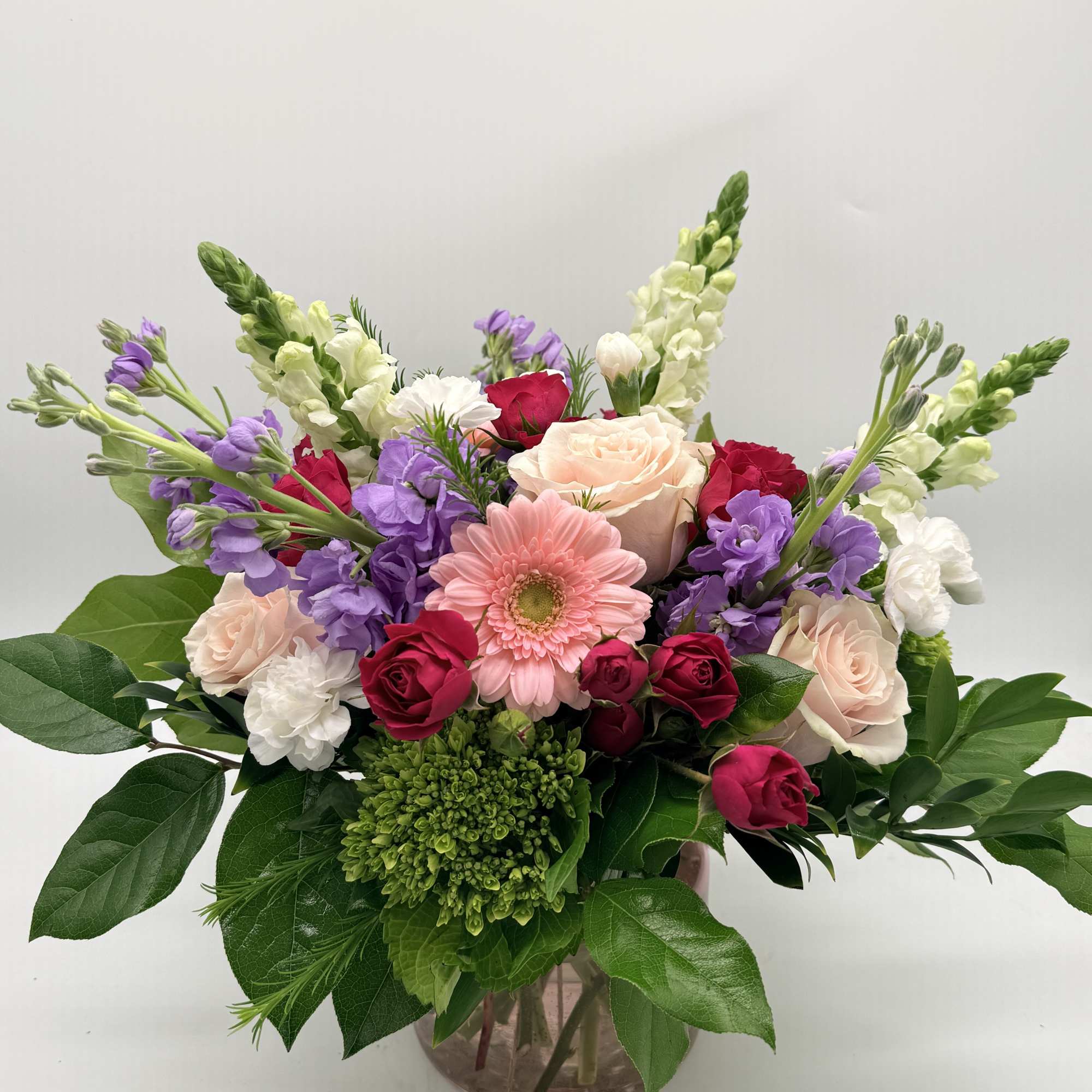 A dreamy mix of blooms designed in a delicate pink vase. 

Shades