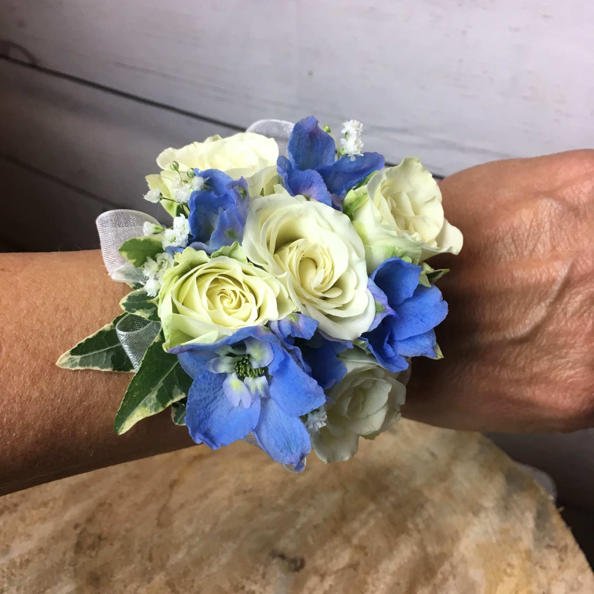 Blue and white wrist corsage with roses and ribbon