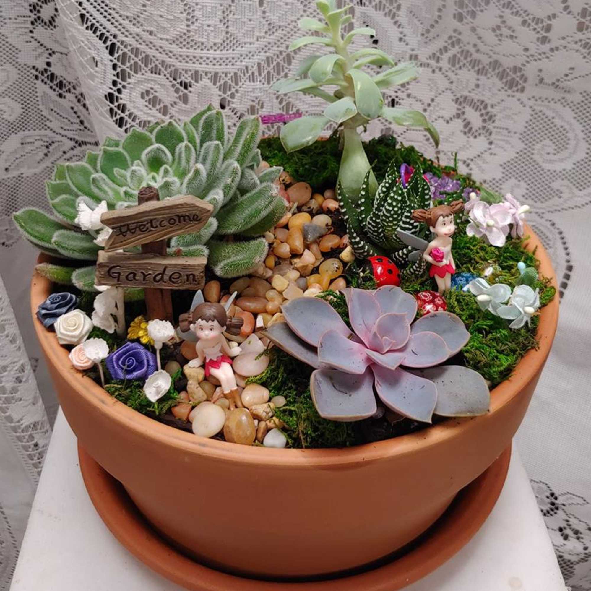 Succulent garden in a terracotta pot with small figurines and decorative stones