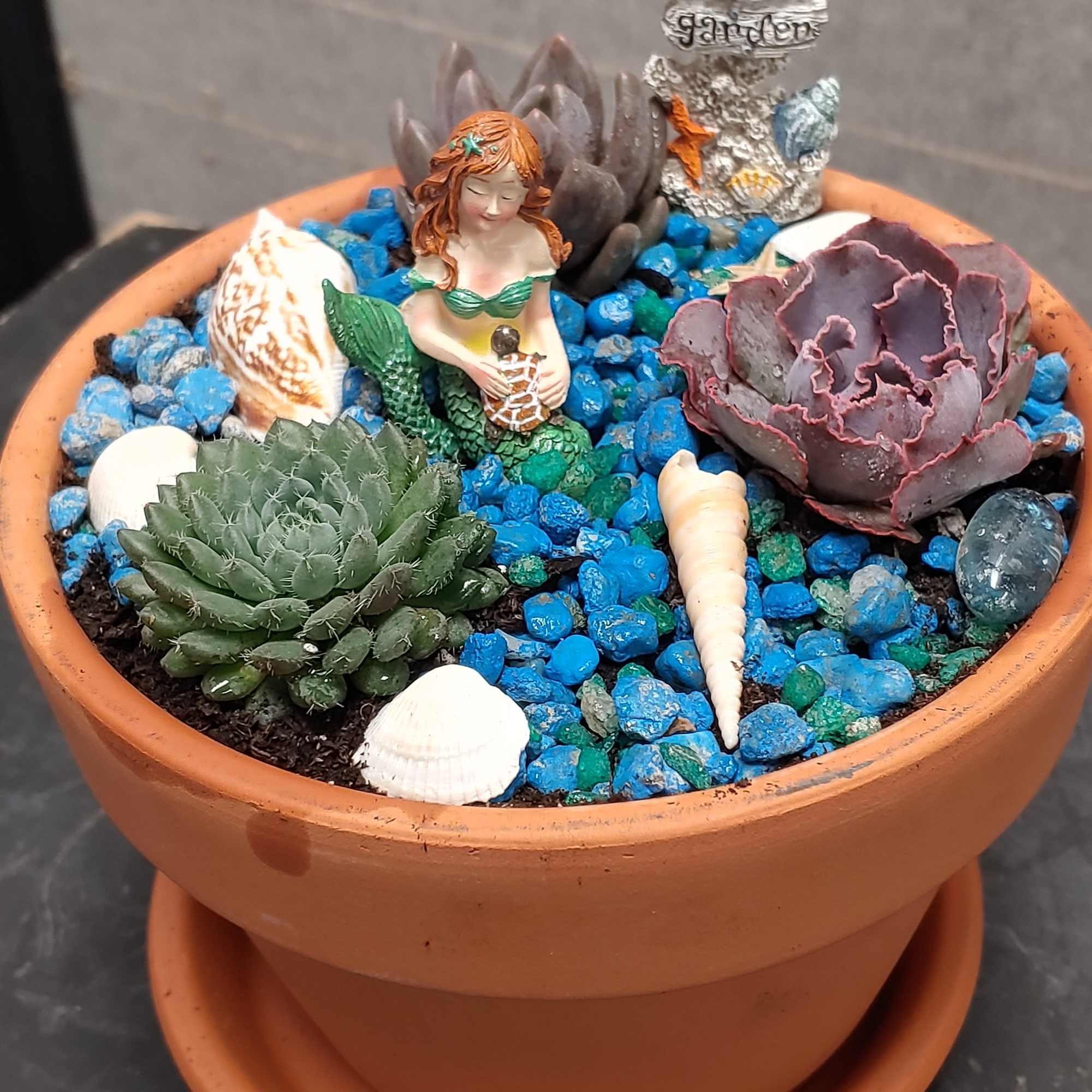 Succulent planter in a terracotta pot with shells and a mermaid figurine