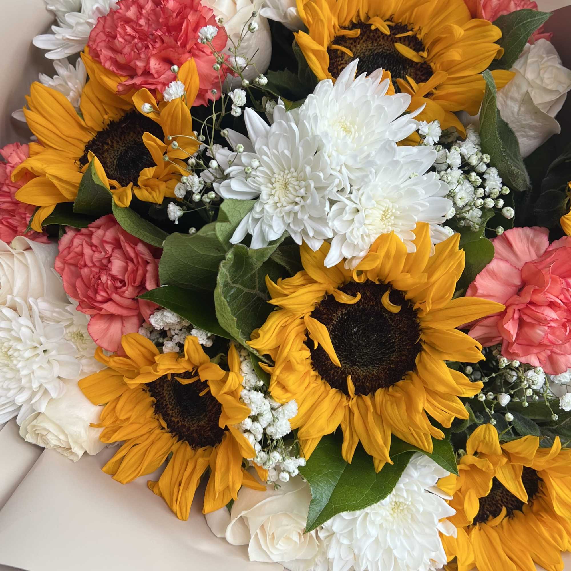 Bouquet of sunflowers, white roses, and pink carnations in beige wrap