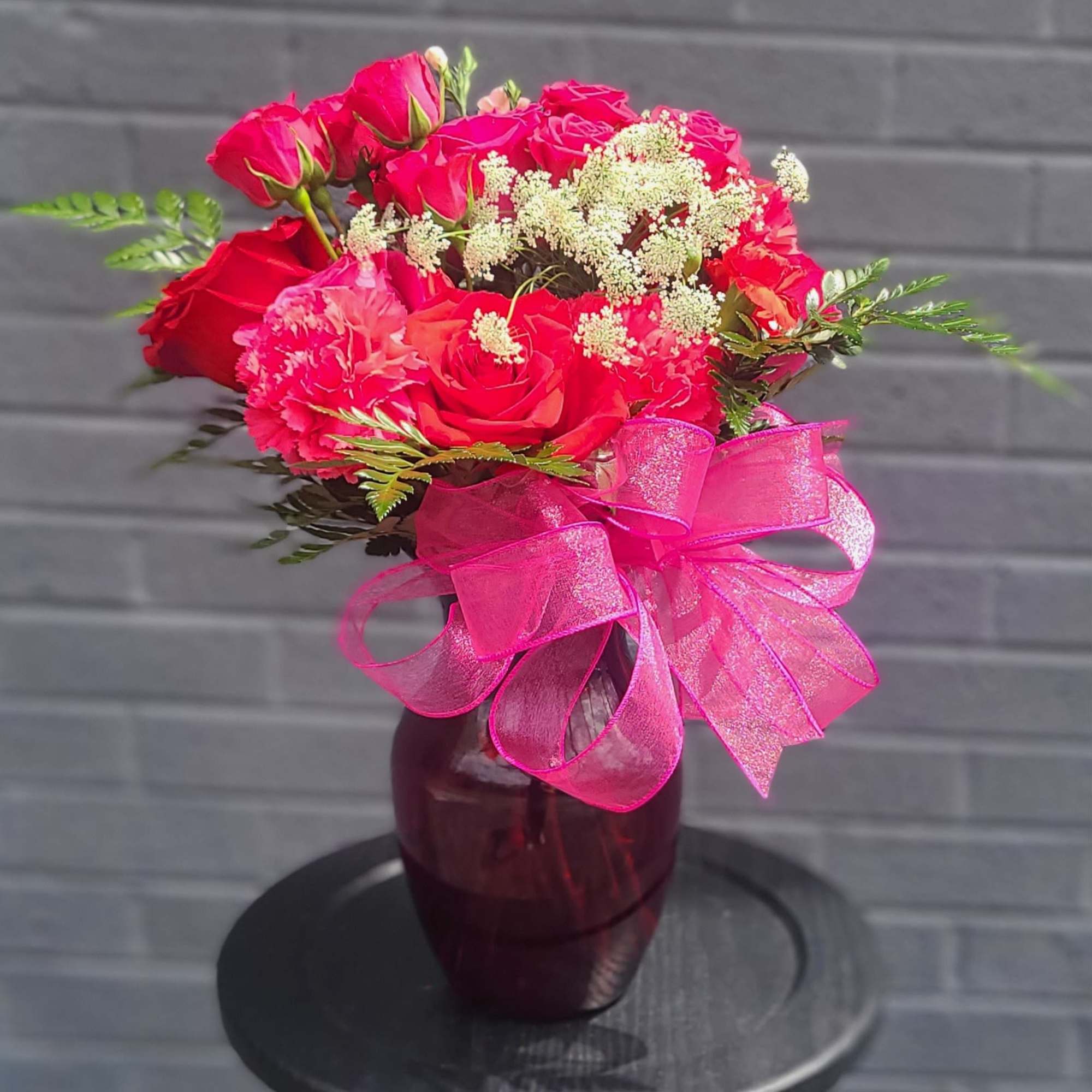Vivid pink and red roses clustered with soft pink carnations make an