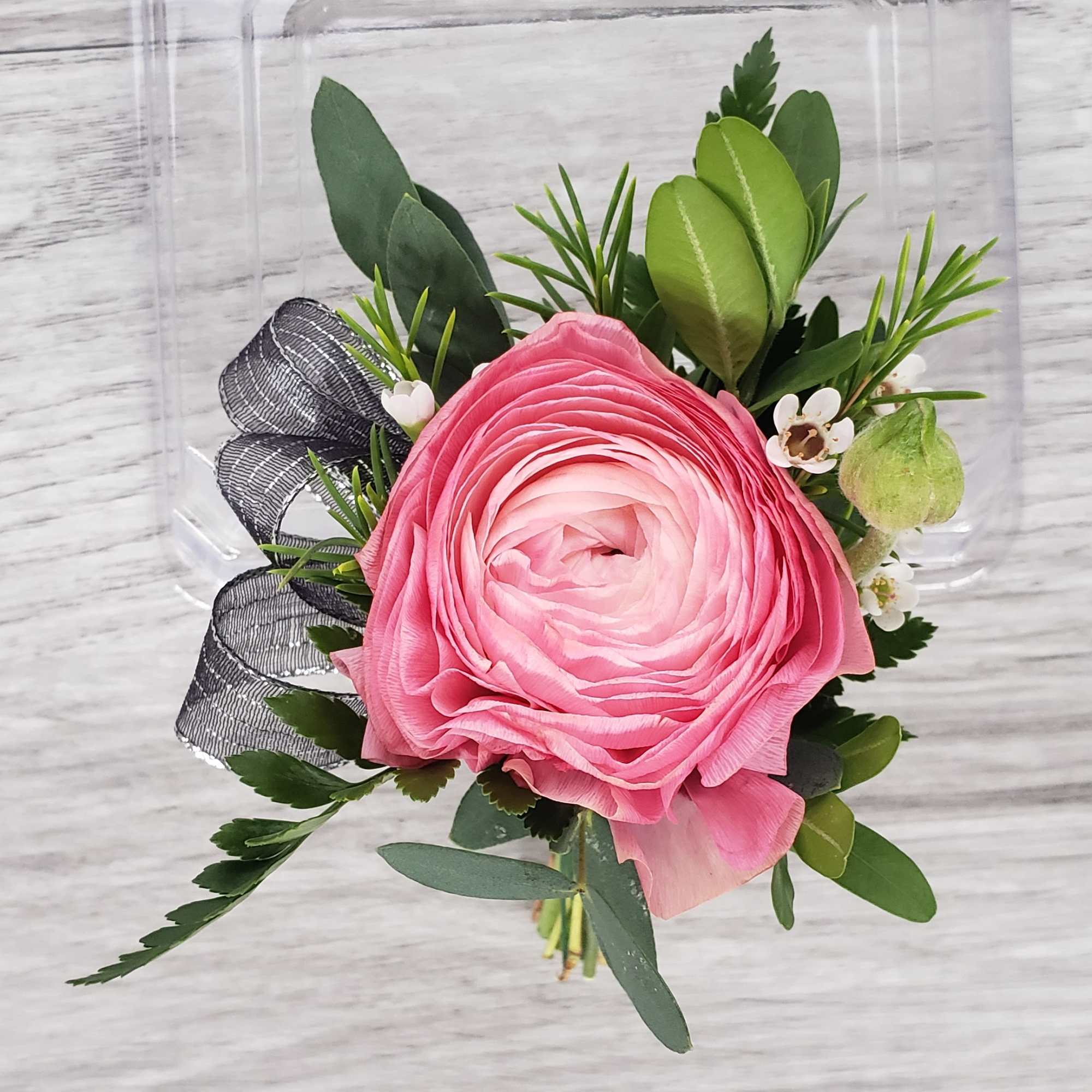 Pink ranunculus bouquet with greenery and a black ribbon