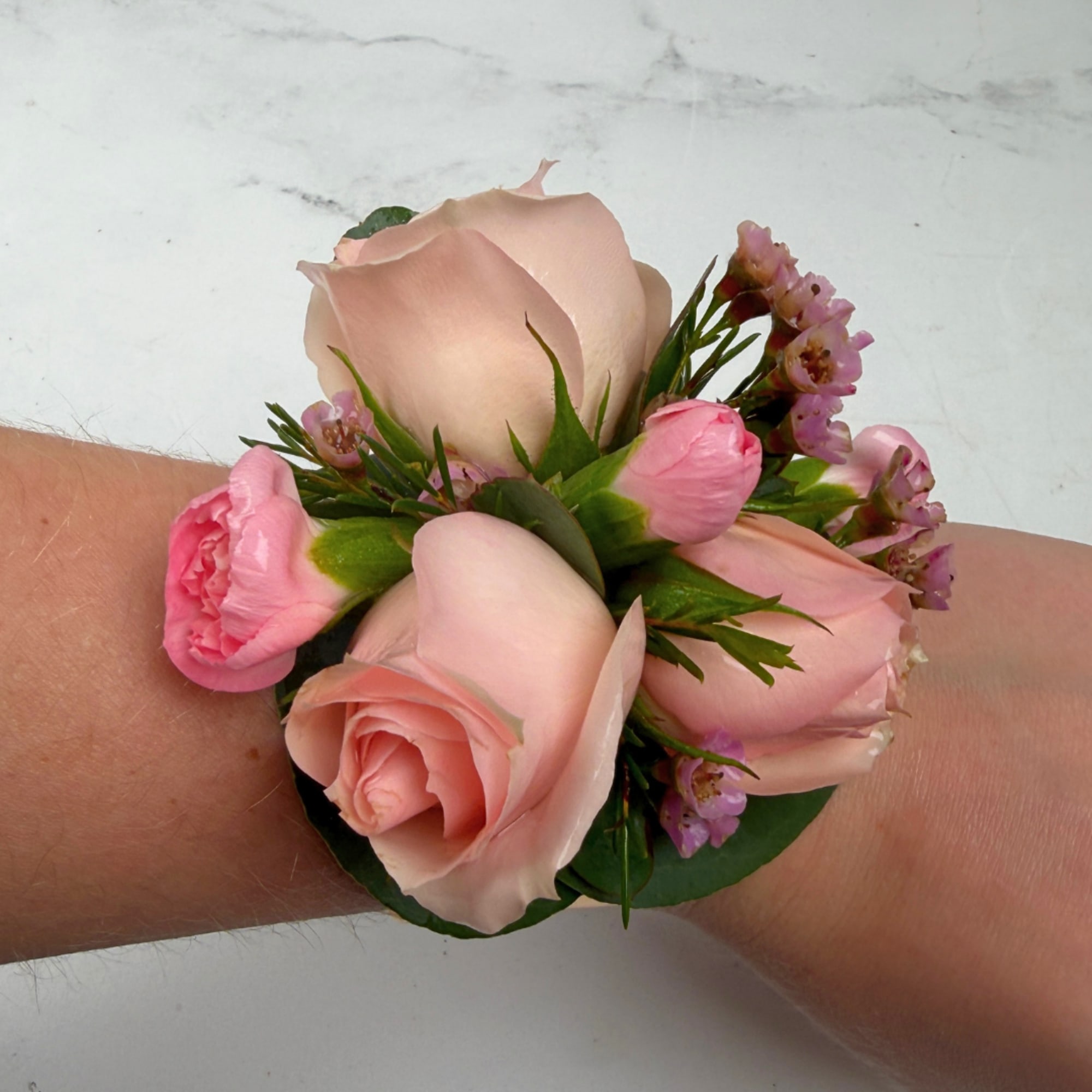 Pale blush roses clustered with pink carnations and tiny pink waxflower fillers