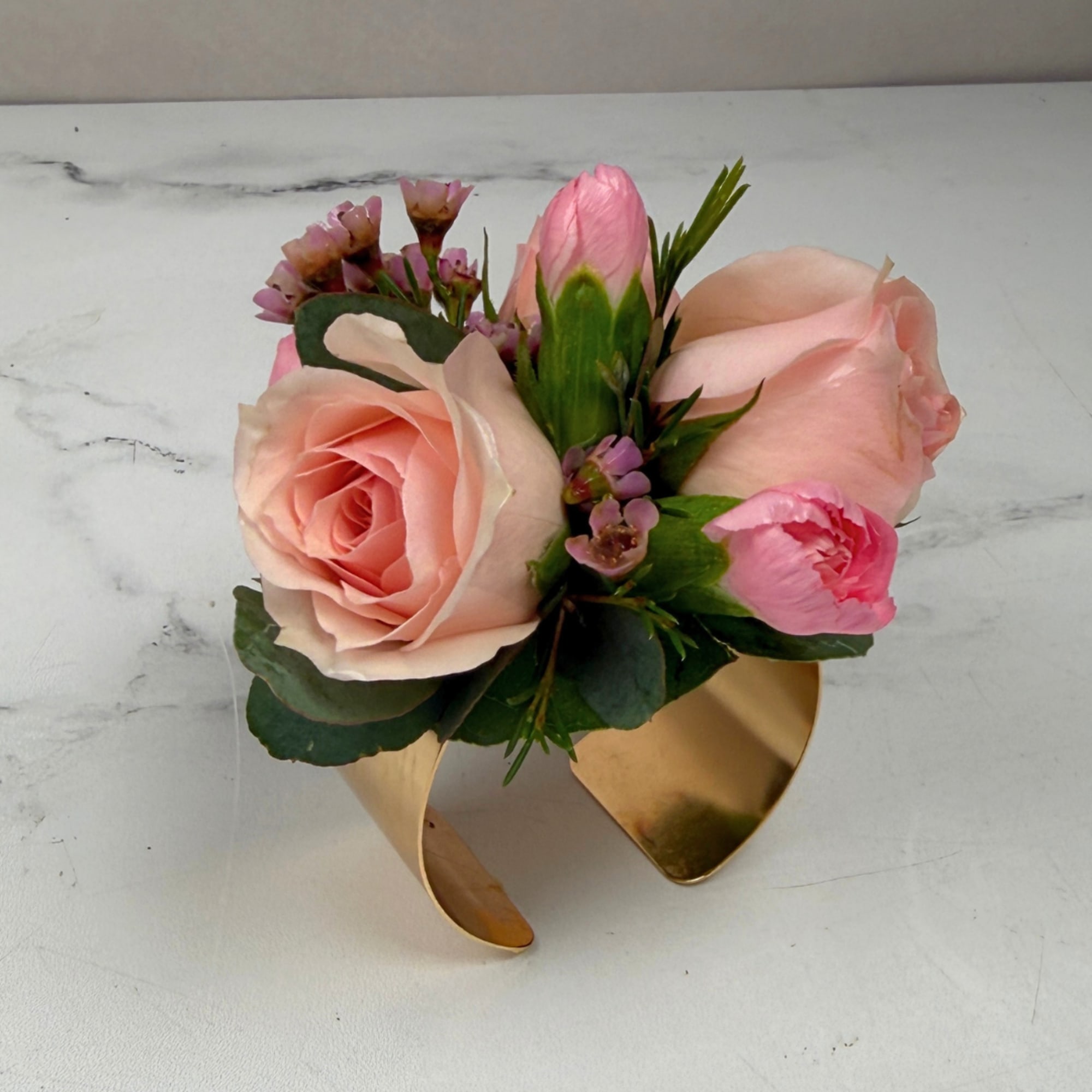 Pale blush roses clustered with pink carnations and tiny pink waxflower fillers