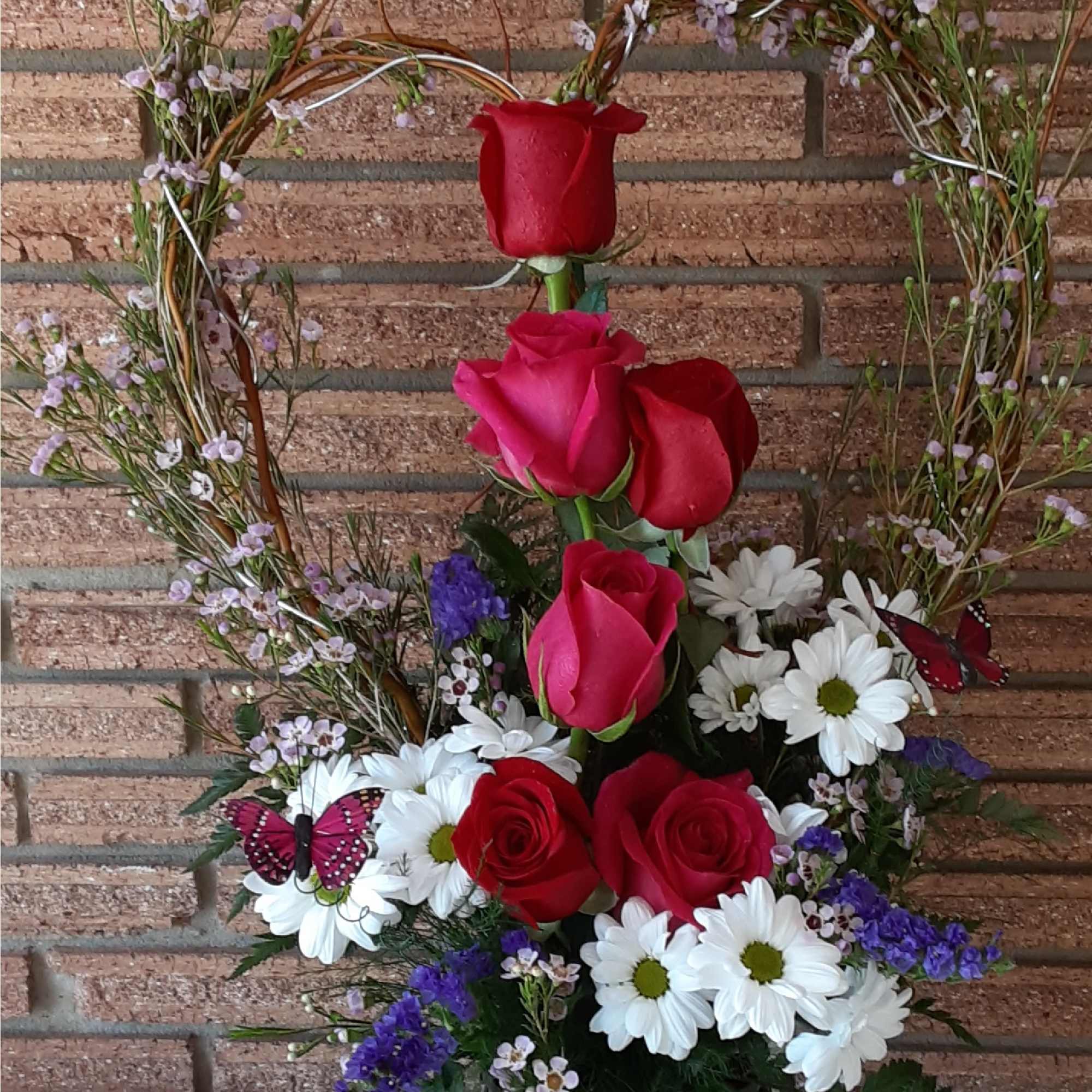 Heart-shaped floral arrangement with red roses and white daisies