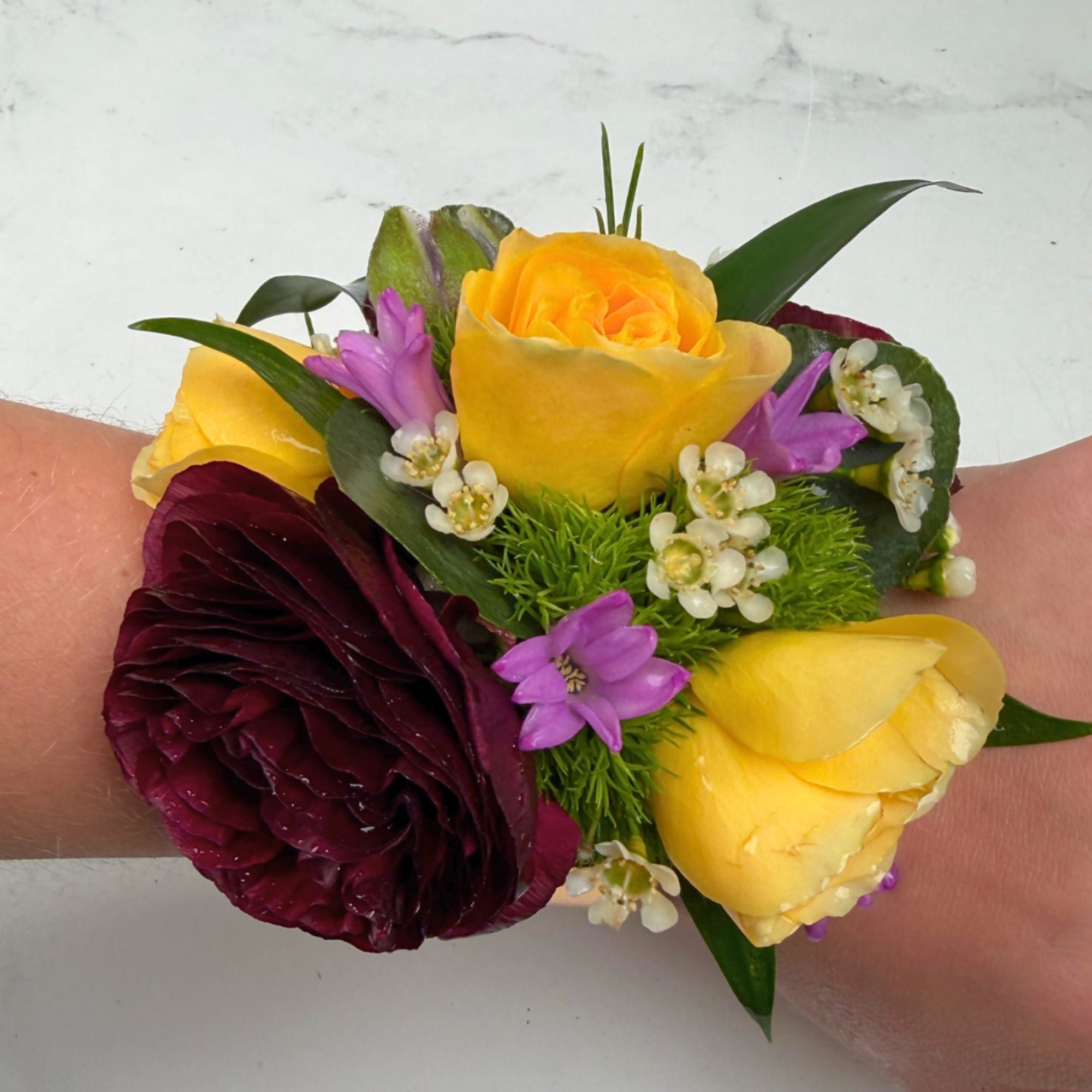 A lush burgundy ranunculus takes center stage in this Velvet Meadow Corsage
