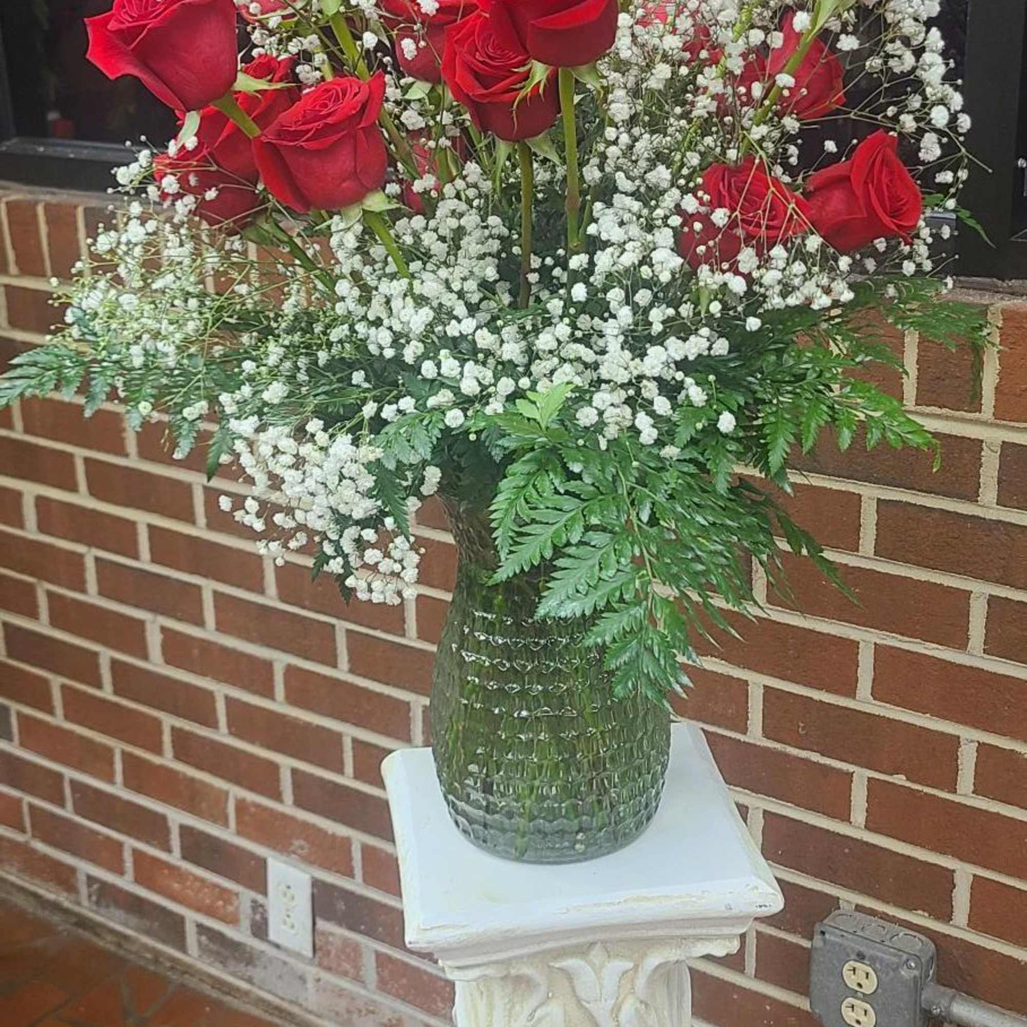 A dense cluster of velvety red roses crowned by airy sprays of