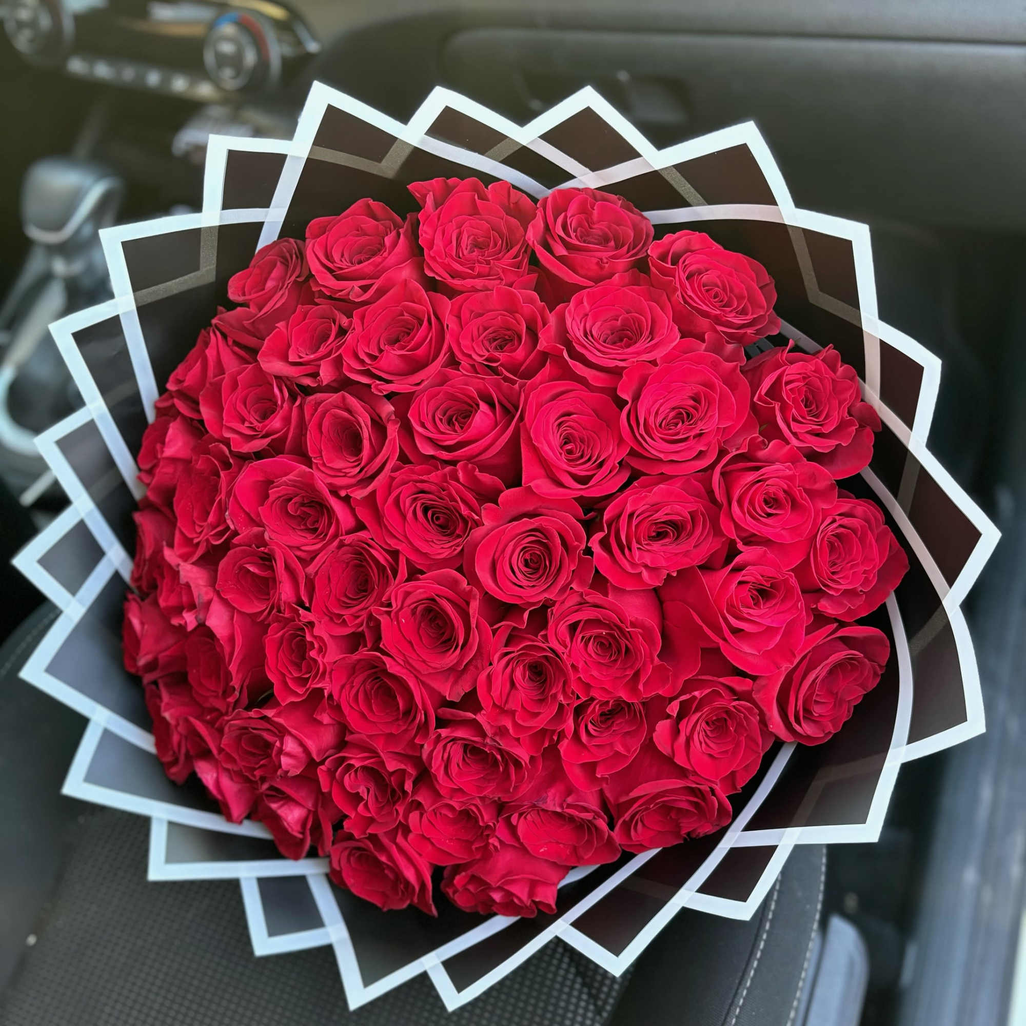 Large bouquet of red roses wrapped in geometric black and white paper