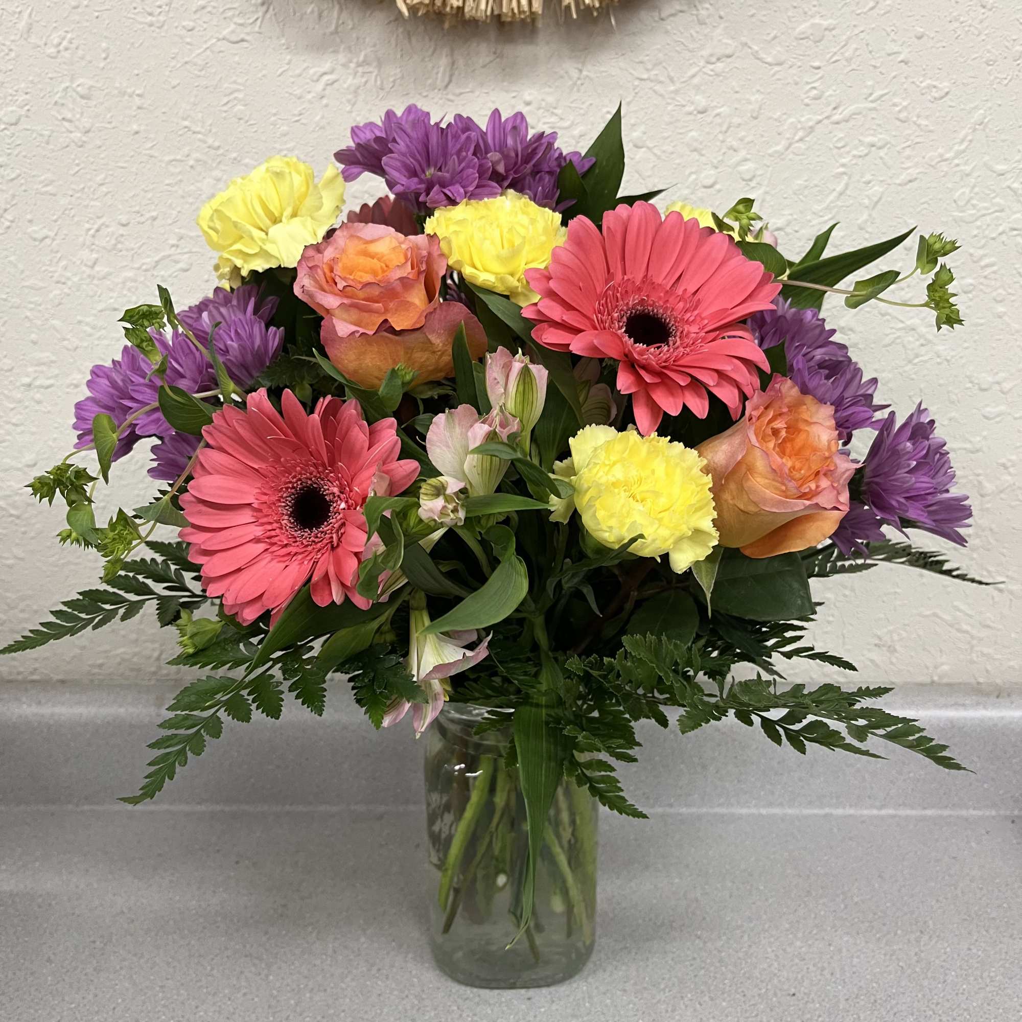 Bright, playful bursts of coral gerbera daisies and free spirit roses make