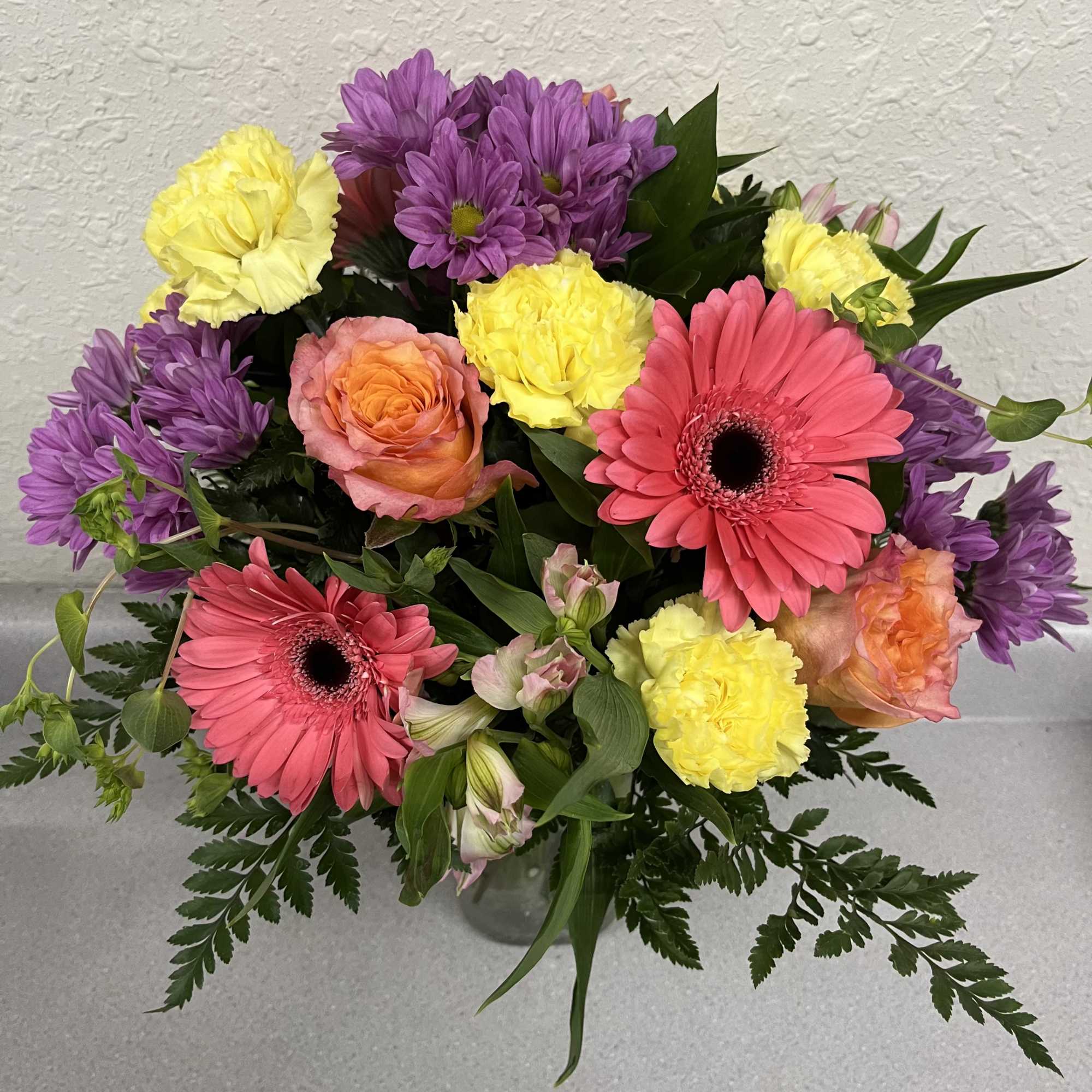 Bright, playful bursts of coral gerbera daisies and free spirit roses make