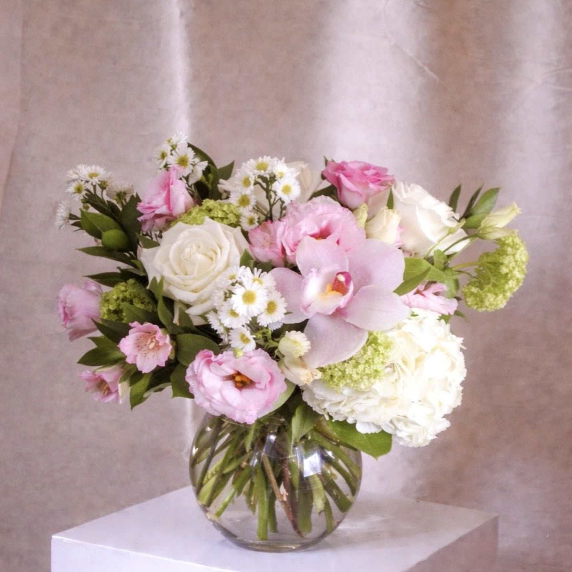A soft, garden-style arrangement in blush and white tones, featuring roses, lisianthus