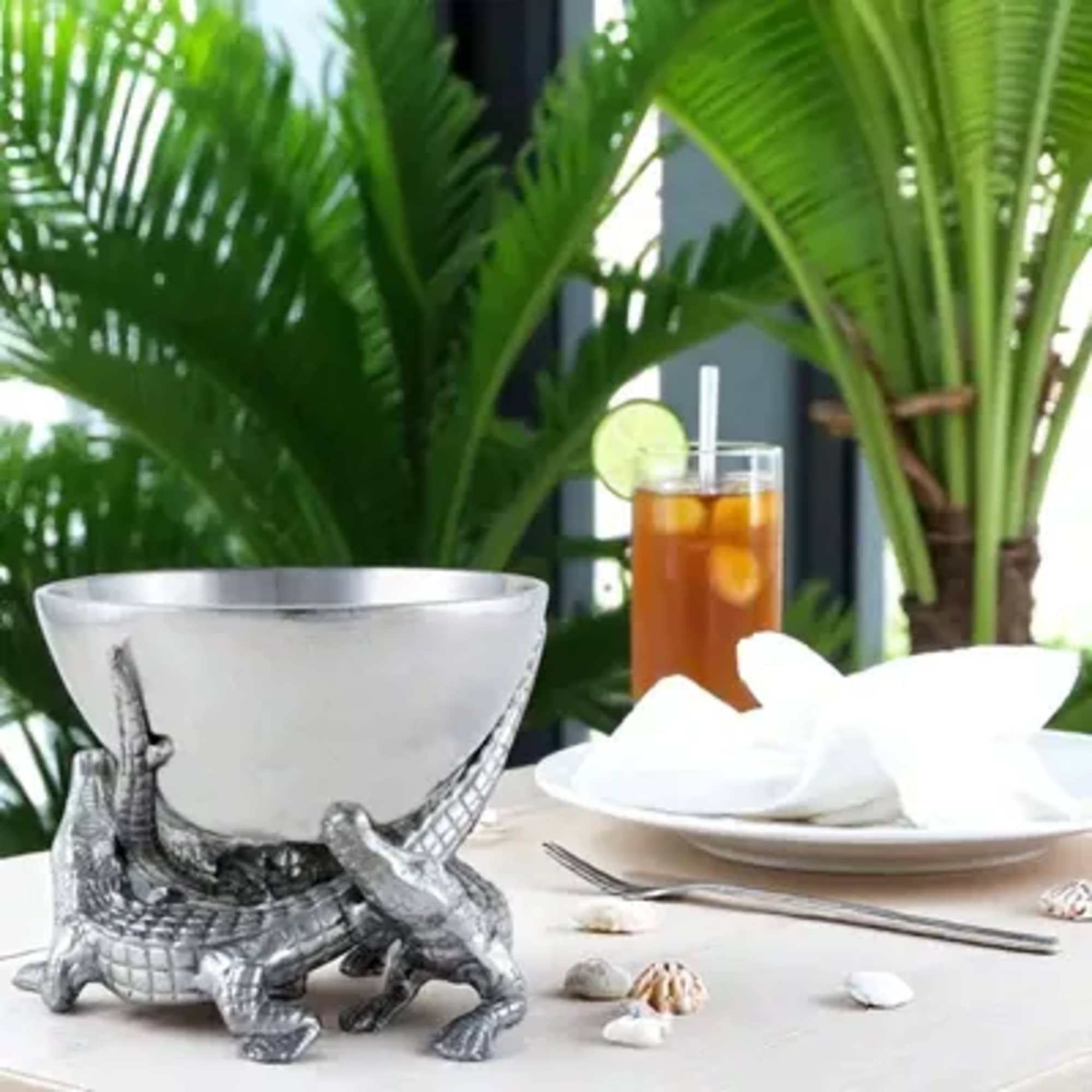 Silver turtle-shaped bowl on a table with a drink and white napkin